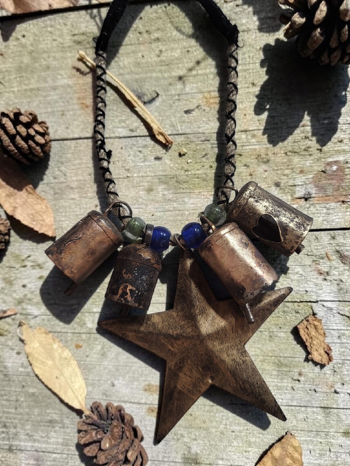 Rustic bells Christmas necklace featuring metal bells and a wooden star on a natural background.