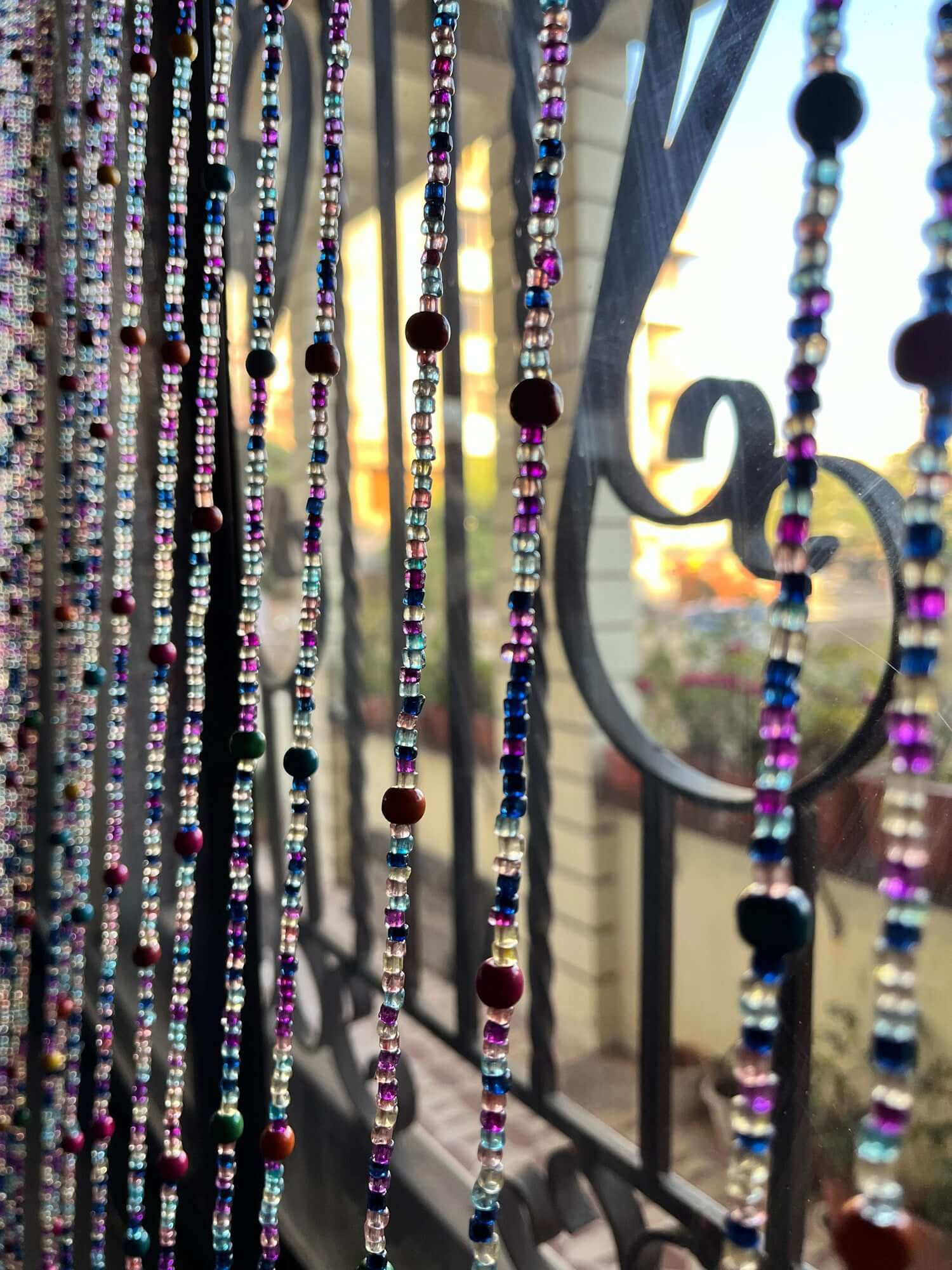 Handmade colorful glass bead strands with jingle bells—perfect for doorways or wall décor. Eco-friendly and crafted by women's artisans in India.