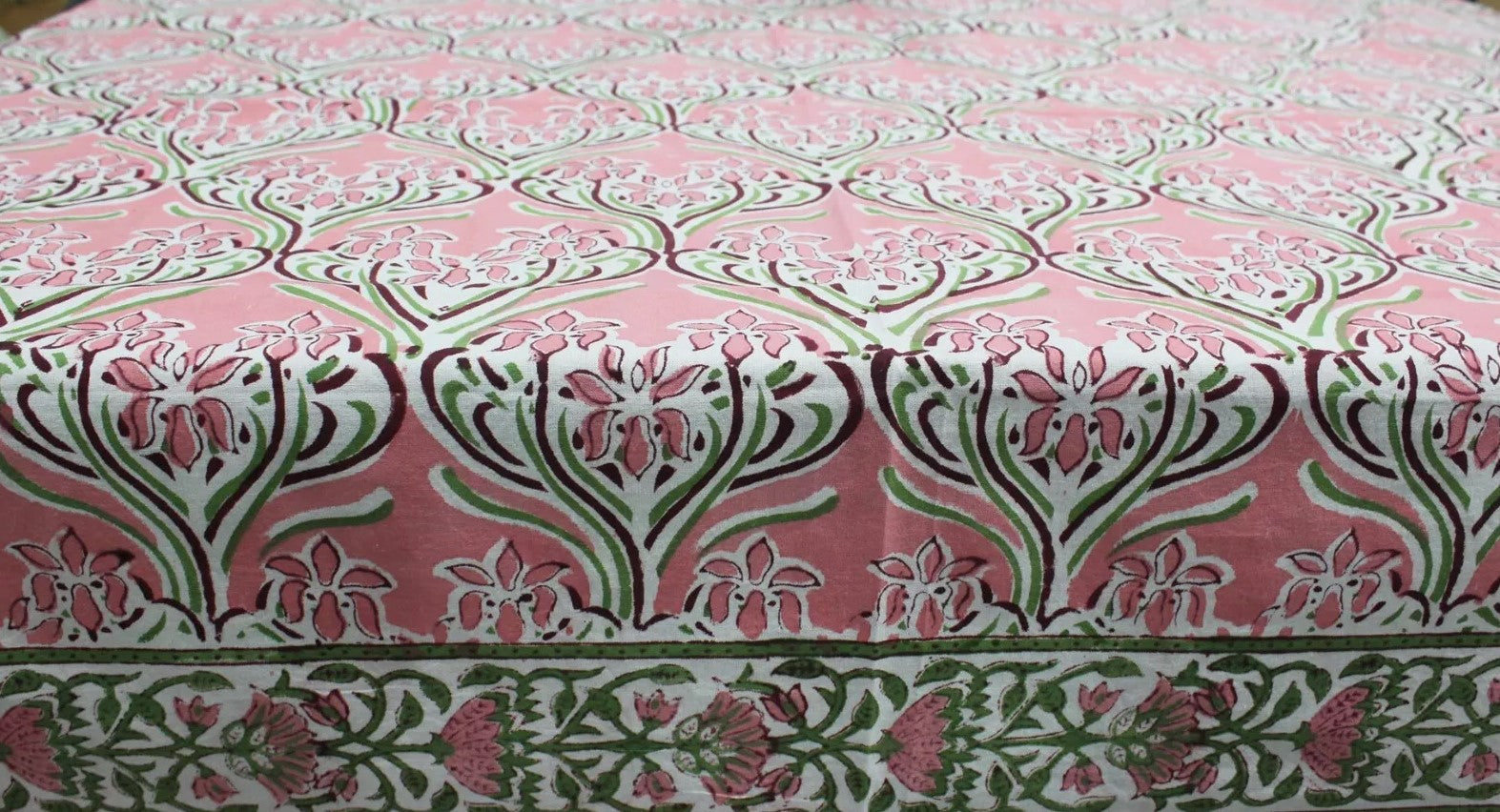 Hand block print tablecloth featuring floral patterns in pink and green, perfect for dining and festive occasions.