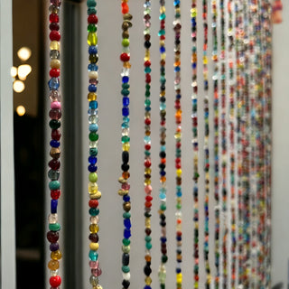 Colorful bohemian glass beaded curtain with decorative bells, adding vibrant charm to any space.