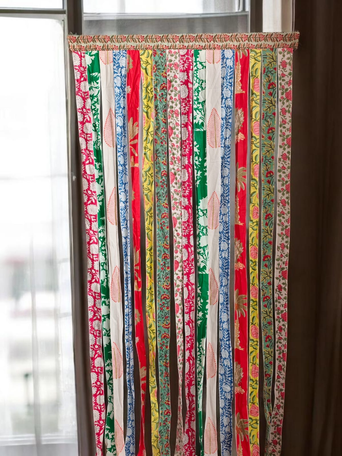 Colorful striped curtain with various patterns in a room with a window.