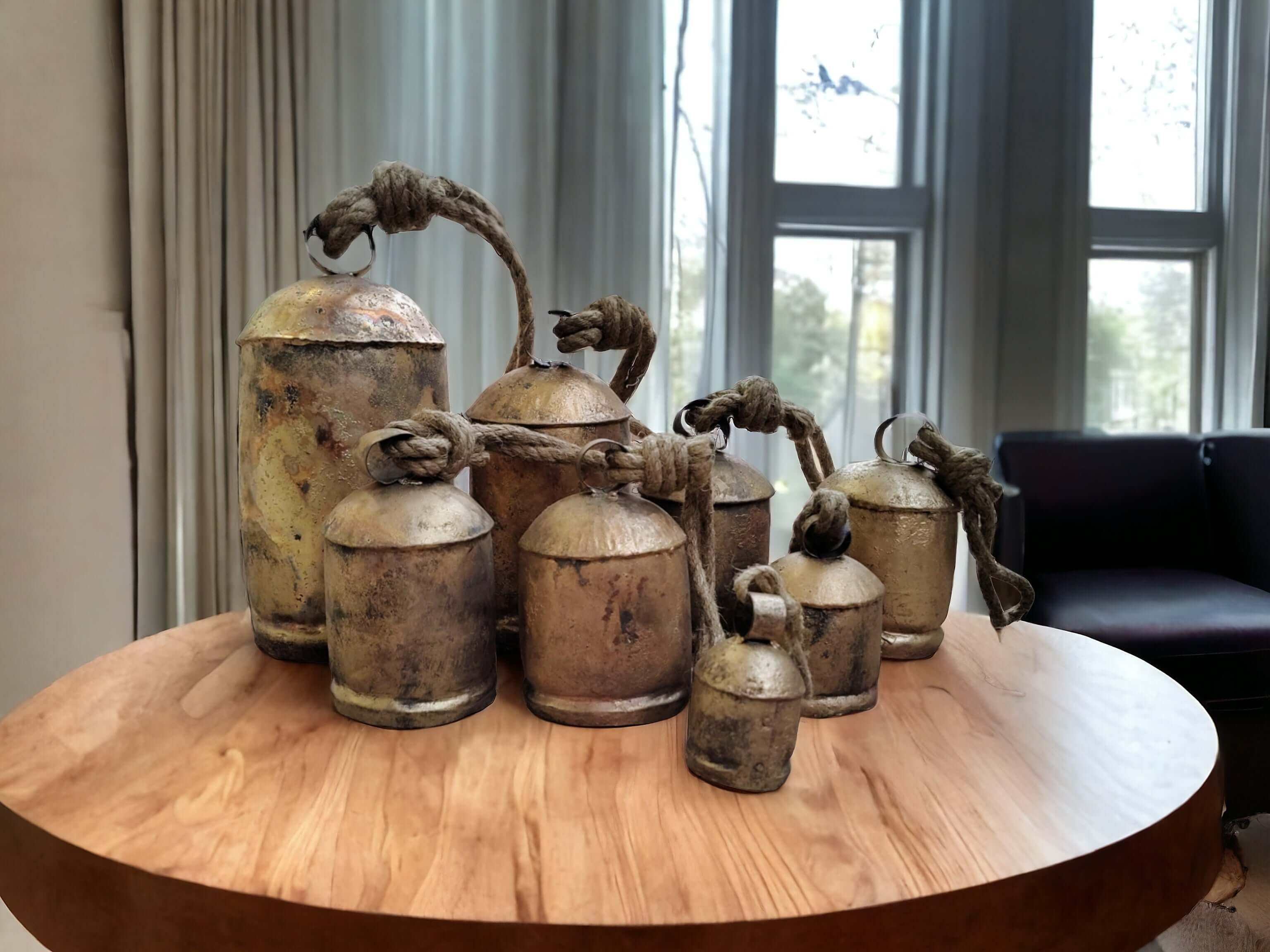 Giant Rustic Cow Bells Decor – 8 Piece Antique Bell Collection on a wooden table indoors.