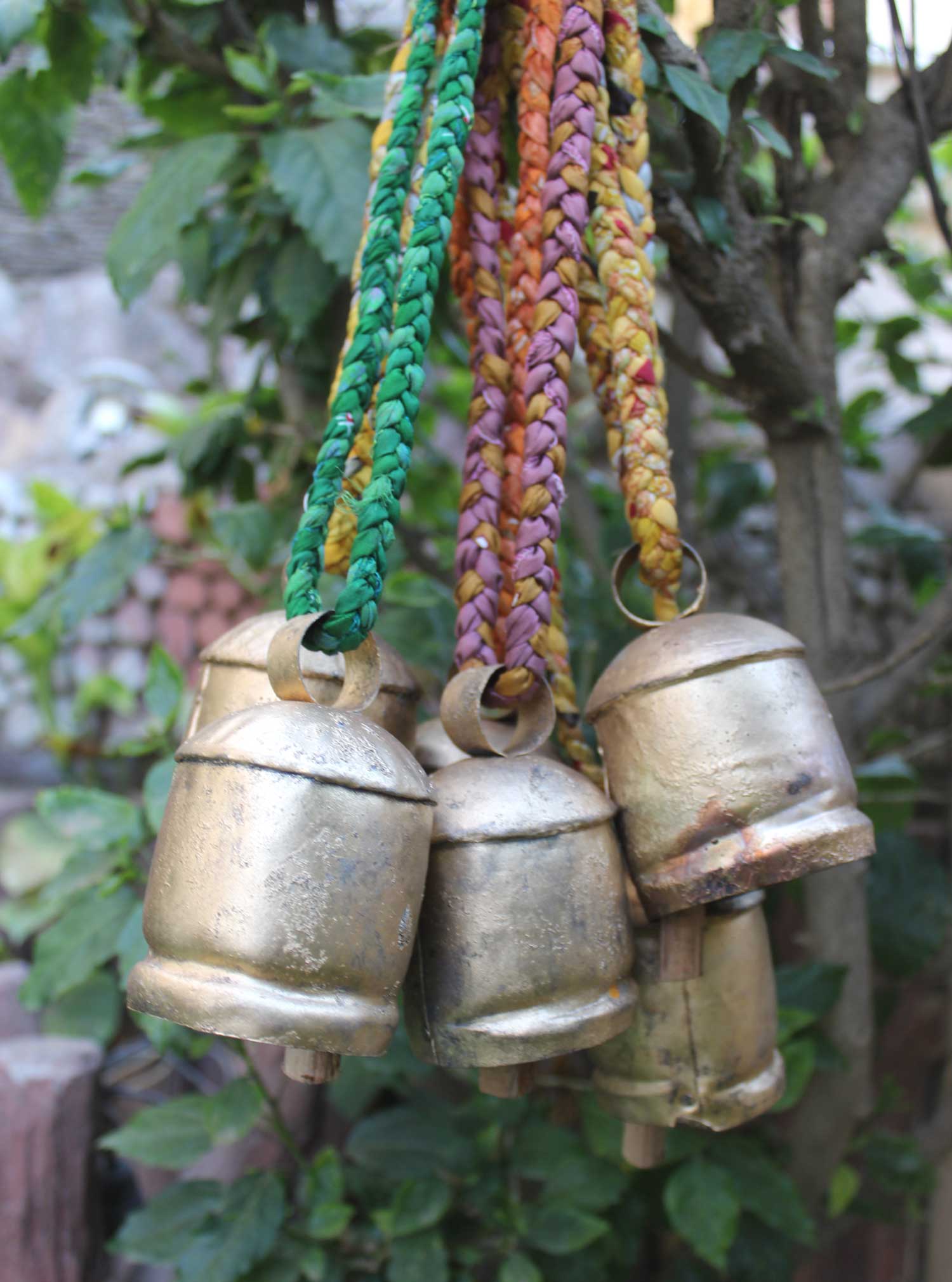 Set of 6 rustic vintage tin cow bells with braided sari fabric handles, perfect for garden decor and handcrafted crafts.