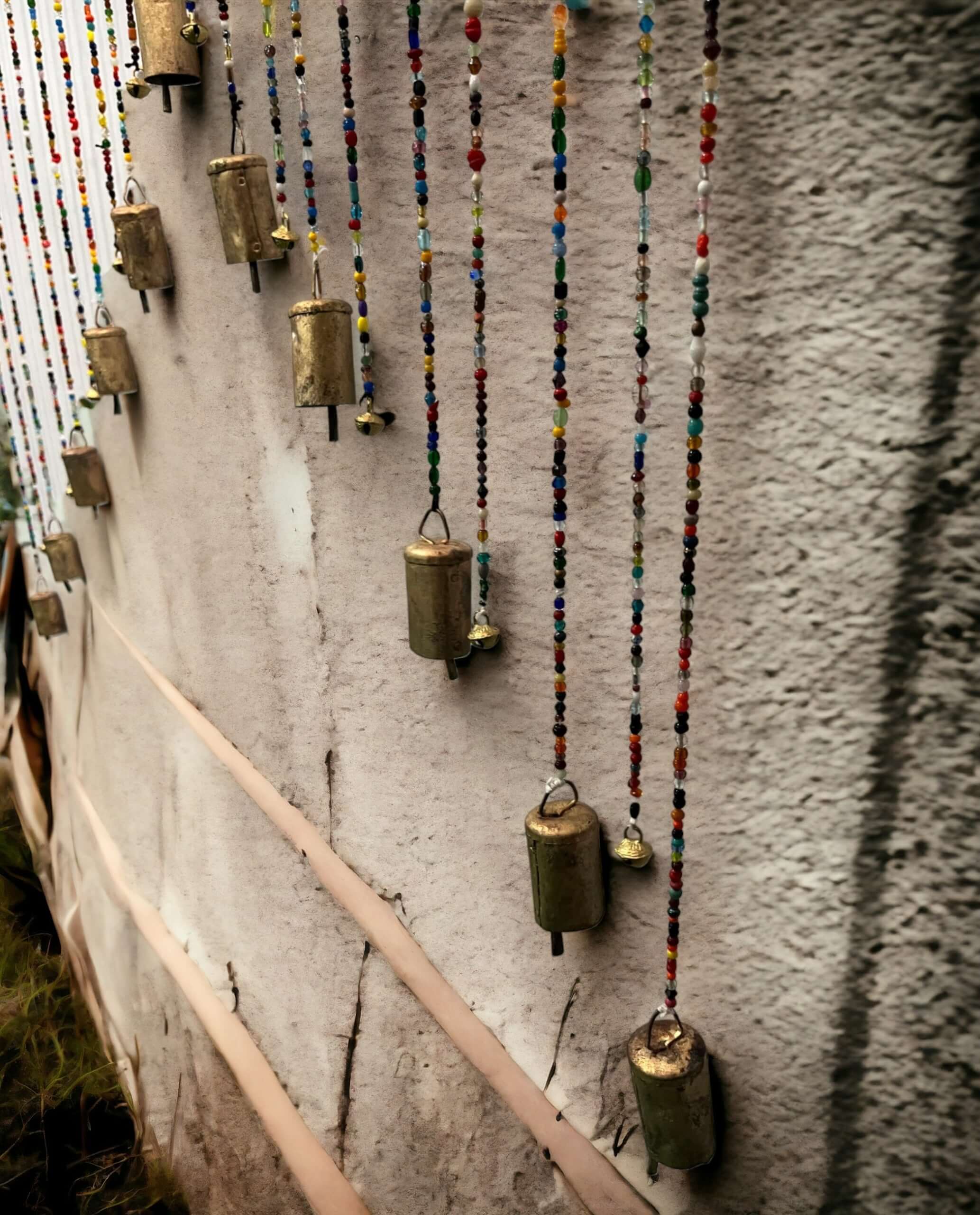 Colorful beaded wall hanging with brass bells for bohemian home decor, showcasing vibrant glass beads.
