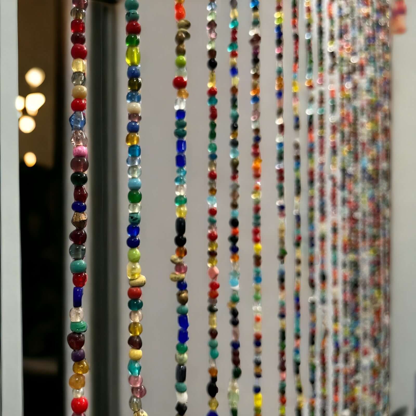 Colorful beaded doorway garland with unique glass beads and jingle bells, perfect for boho home décor and room dividers.