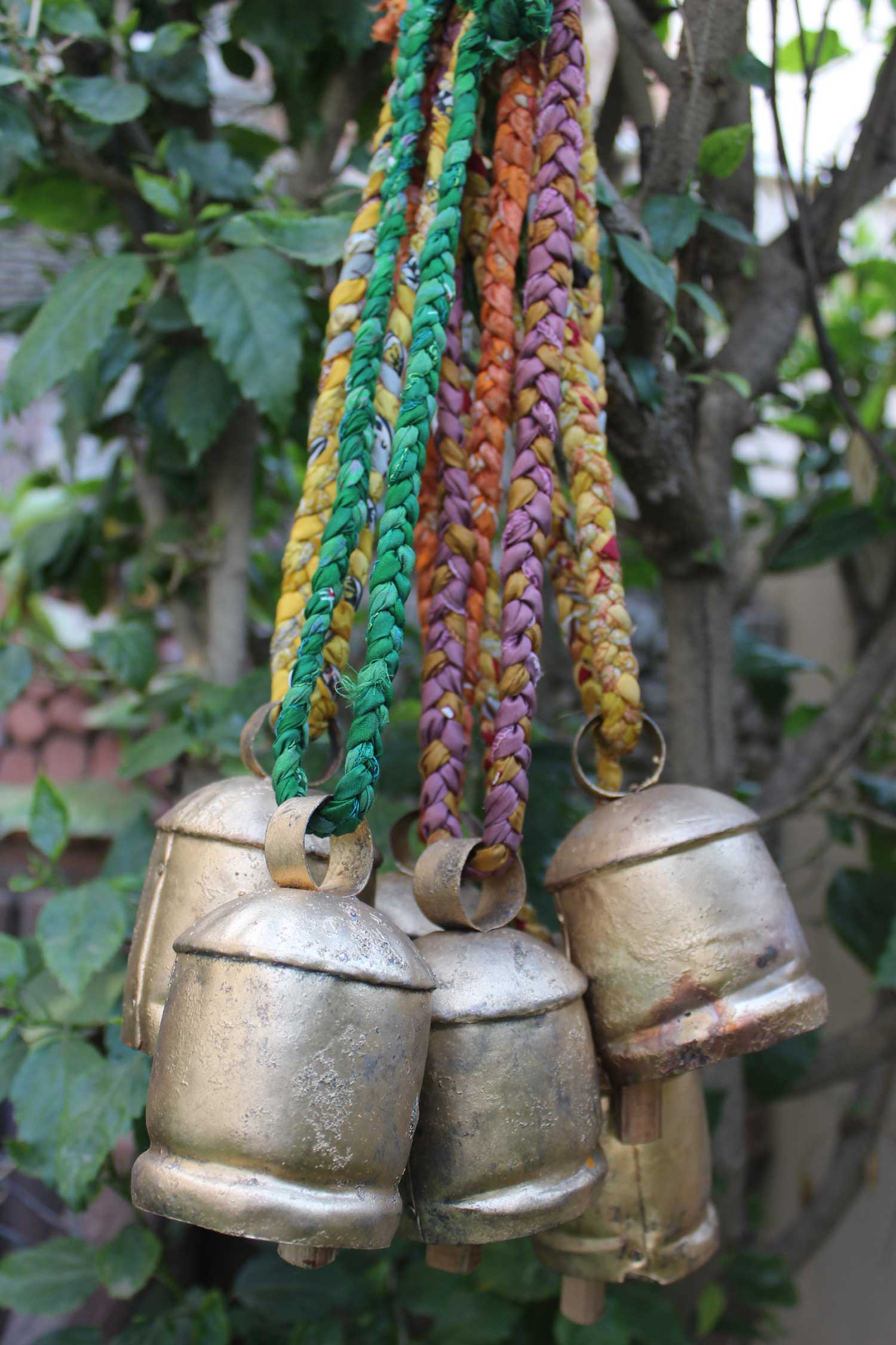 Set of 6 antique tin cow bells with braided sari fabric handle, perfect for rustic garden decorations and vintage crafts.