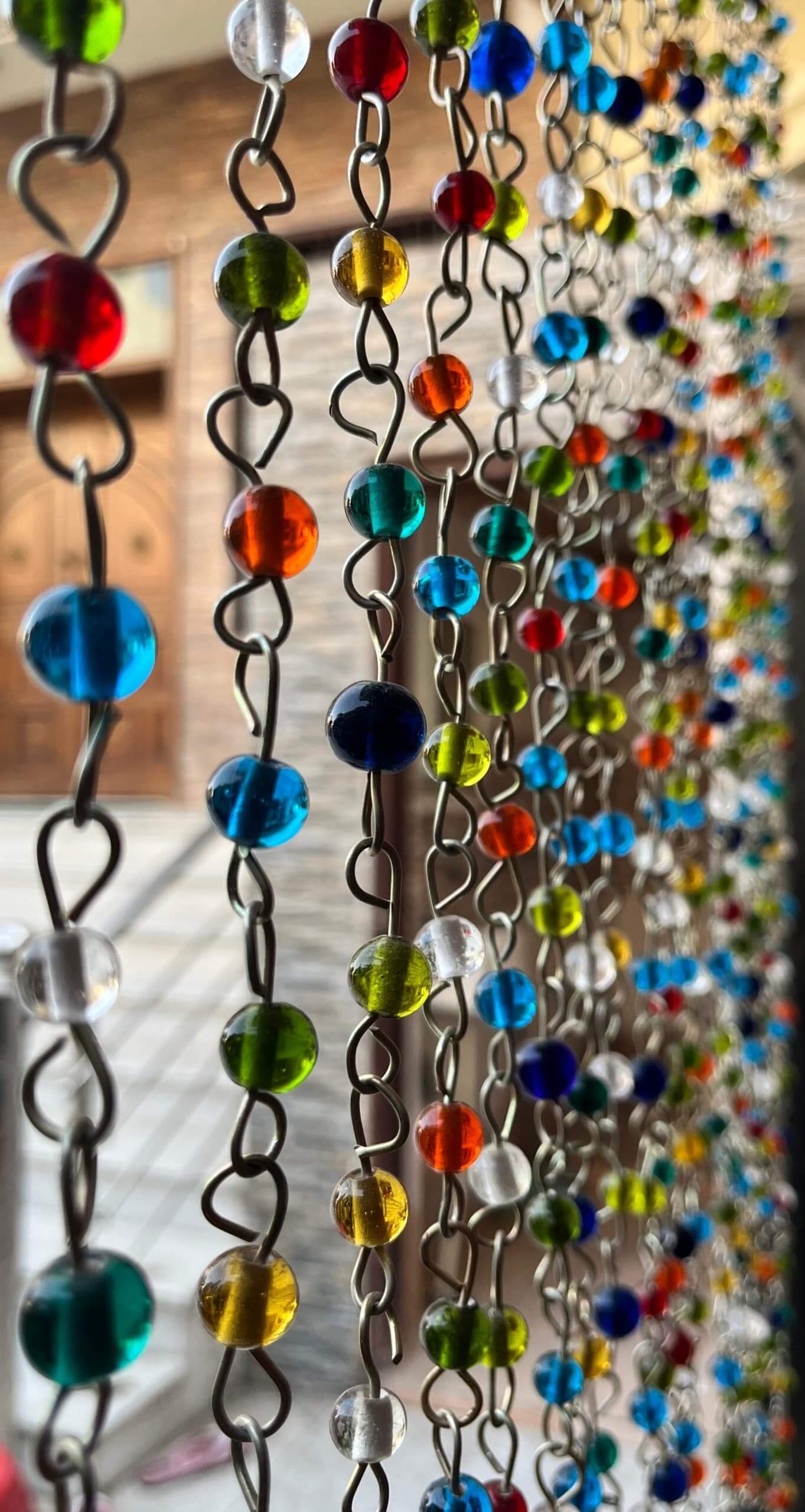 Colorful bohemian beaded curtain chains with jingle bells, perfect for hippie door decor and stylish doorways.