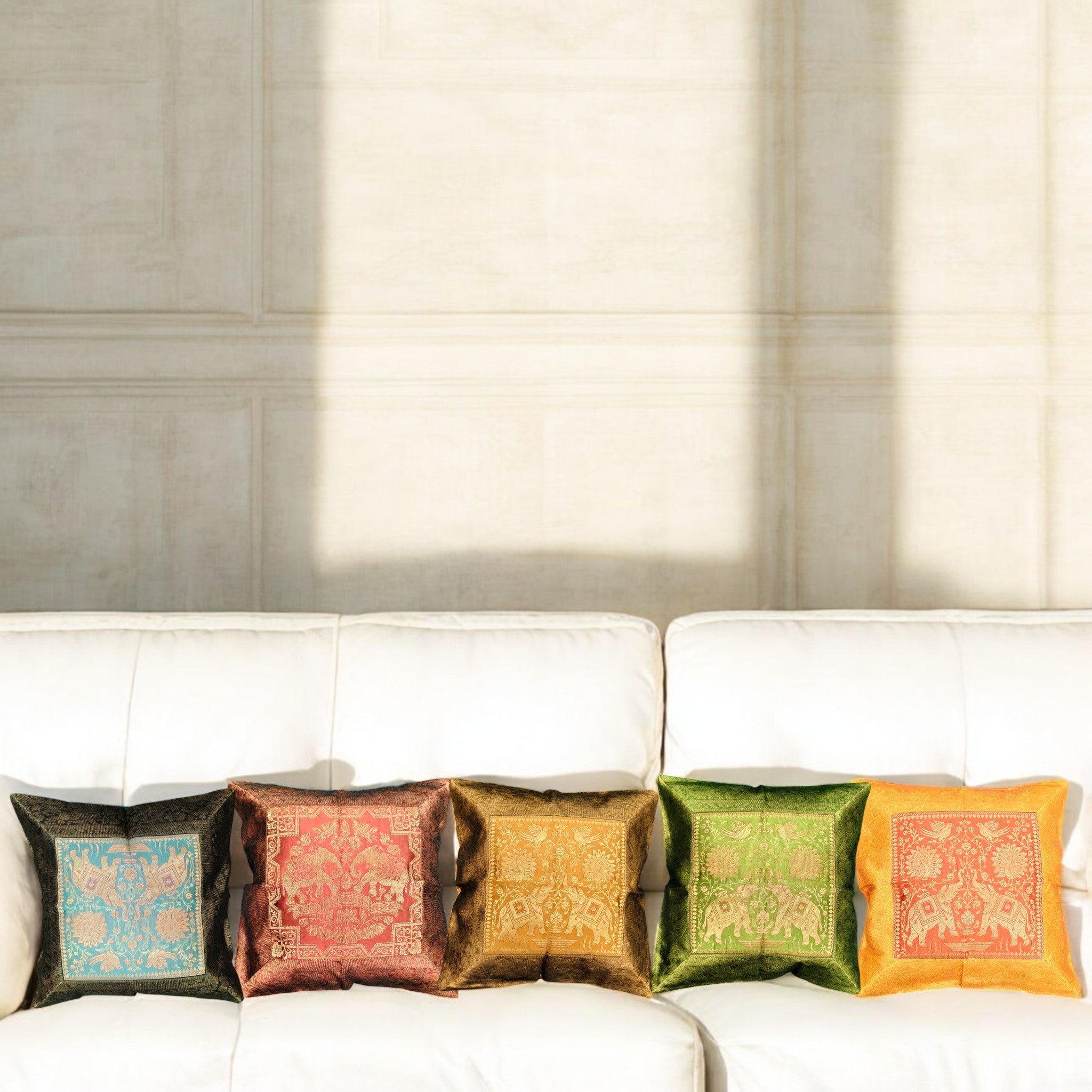 Set of 5 Banarasi silk cushion covers featuring royal elephant designs, arranged on a white sofa for stylish home decor.