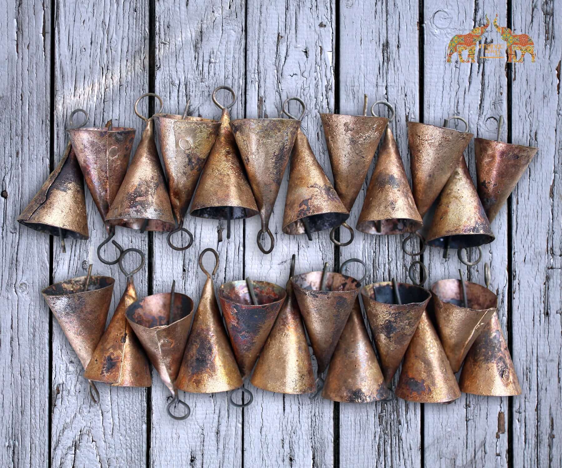 Handmade rustic cone shape bells made from recycled iron, featuring a brass finish, arranged on a wooden surface.