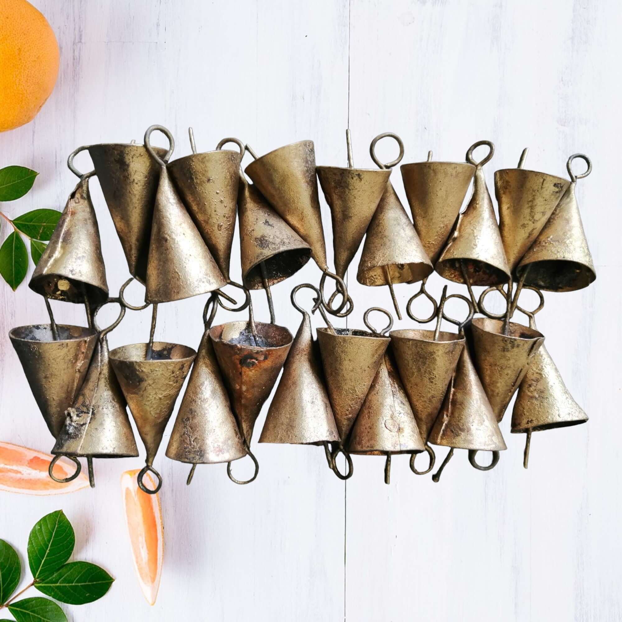 Rustic cone shape bells made from recycled iron, 1.75 inches tall, featuring a brass finish and a soothing tinkle sound.
