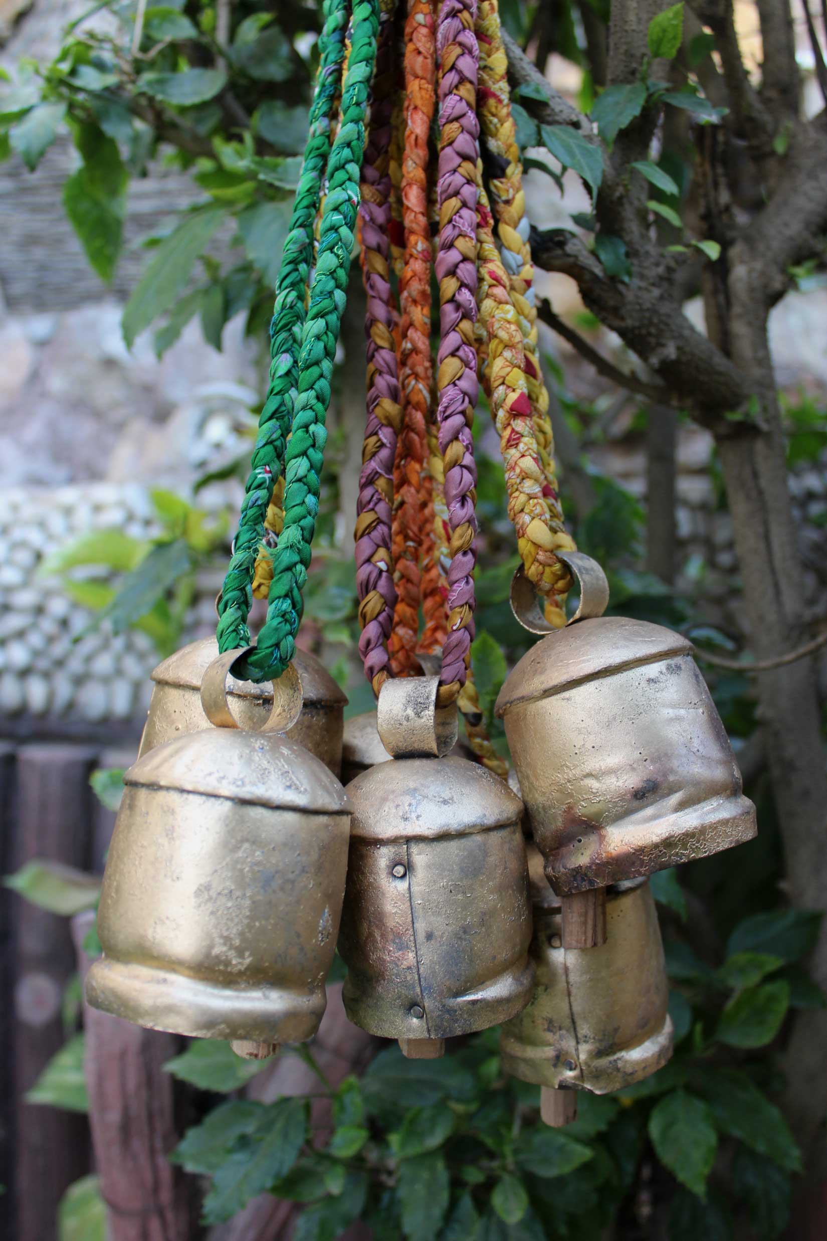 Set of 6 rustic tin cow bells with braided sari fabric handles, perfect for garden decor and vintage crafts.