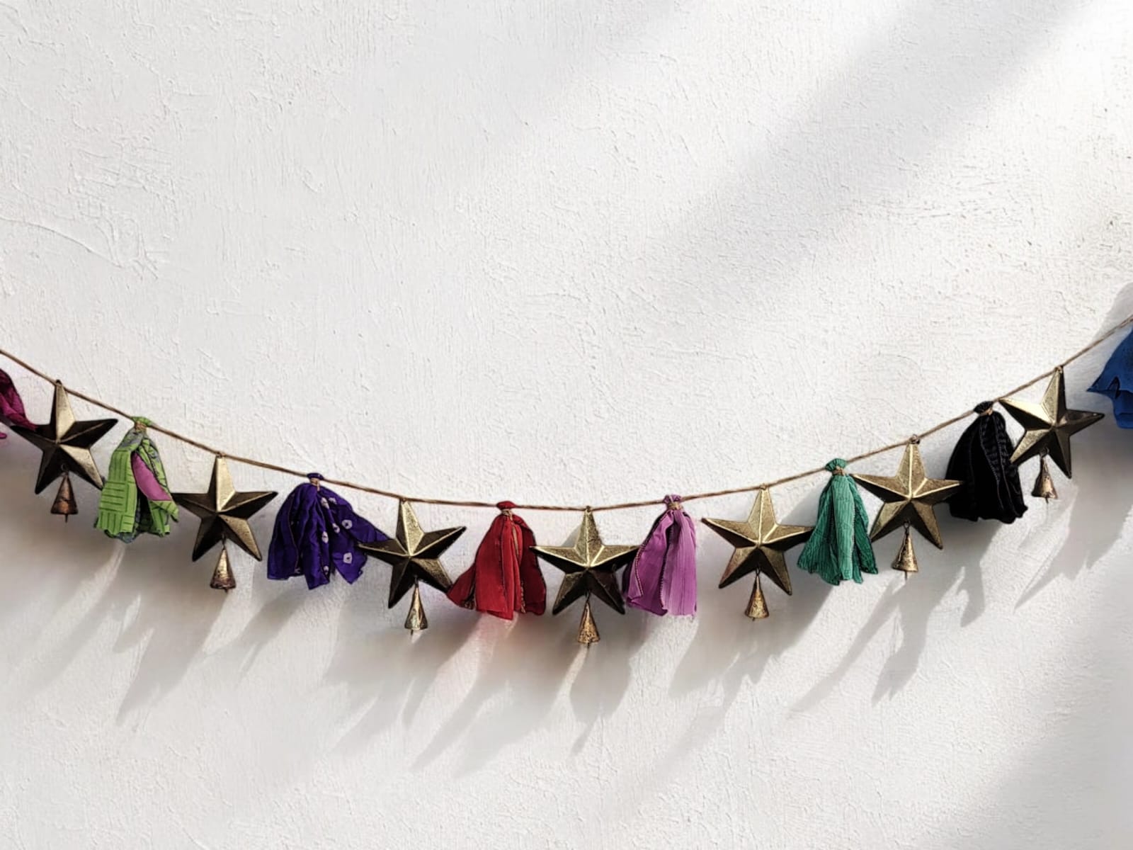 Handmade upcycled silk sari garland with colorful stars and bells for bohemian decor and holiday celebrations.