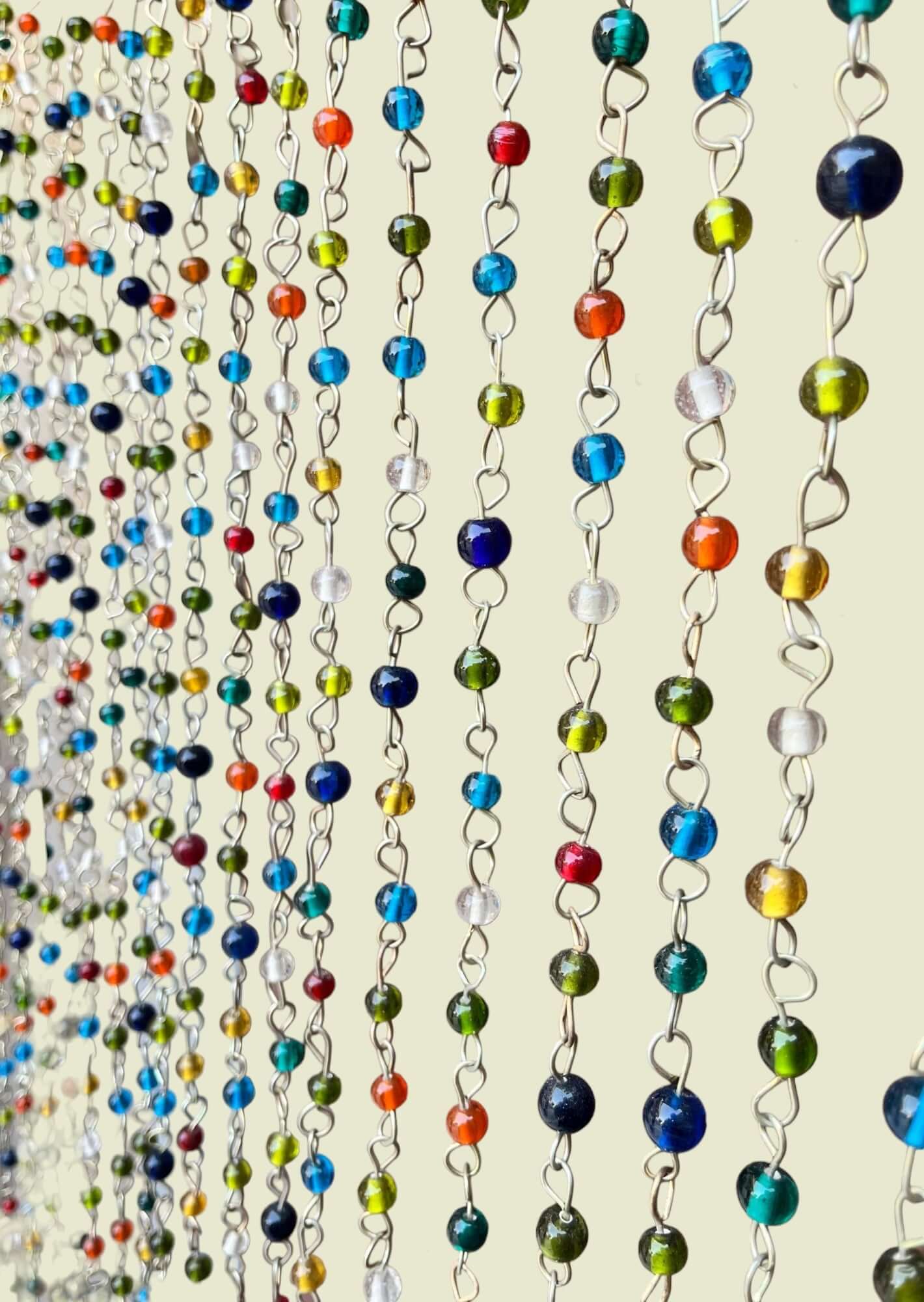 Colorful beaded curtain chains with jingle bells, perfect for bohemian and hippie-inspired decor.