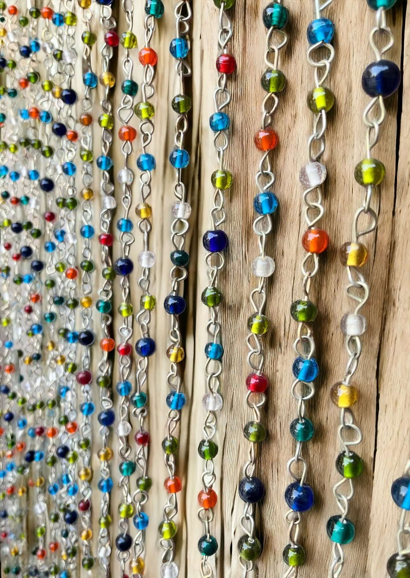 Colorful beaded curtains with vibrant beads hanging in a decorative display, perfect for a bohemian hippie decor.