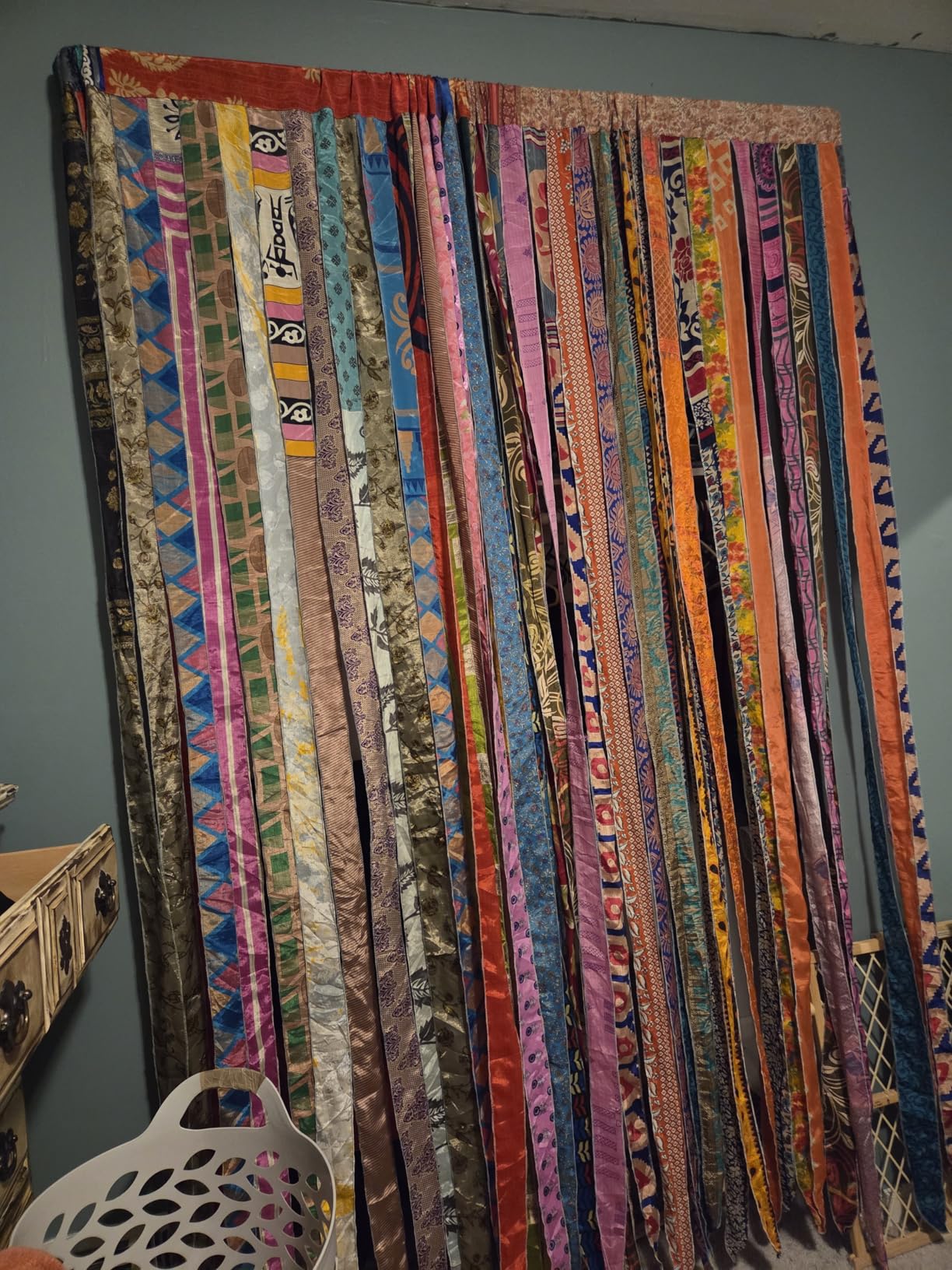 Colorful fabric strip wall hanging against a plain wall