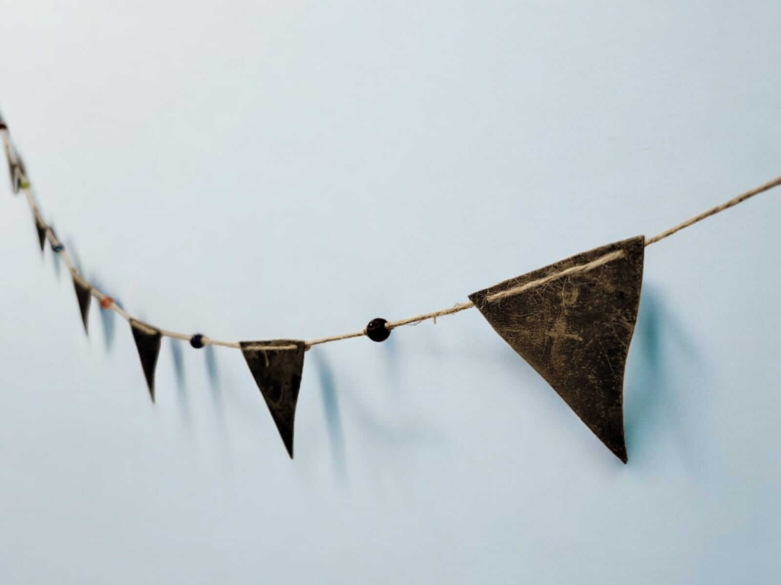 Recycled iron triangle bunting garland with glass beads on jute string, vintage bohemian party decoration.