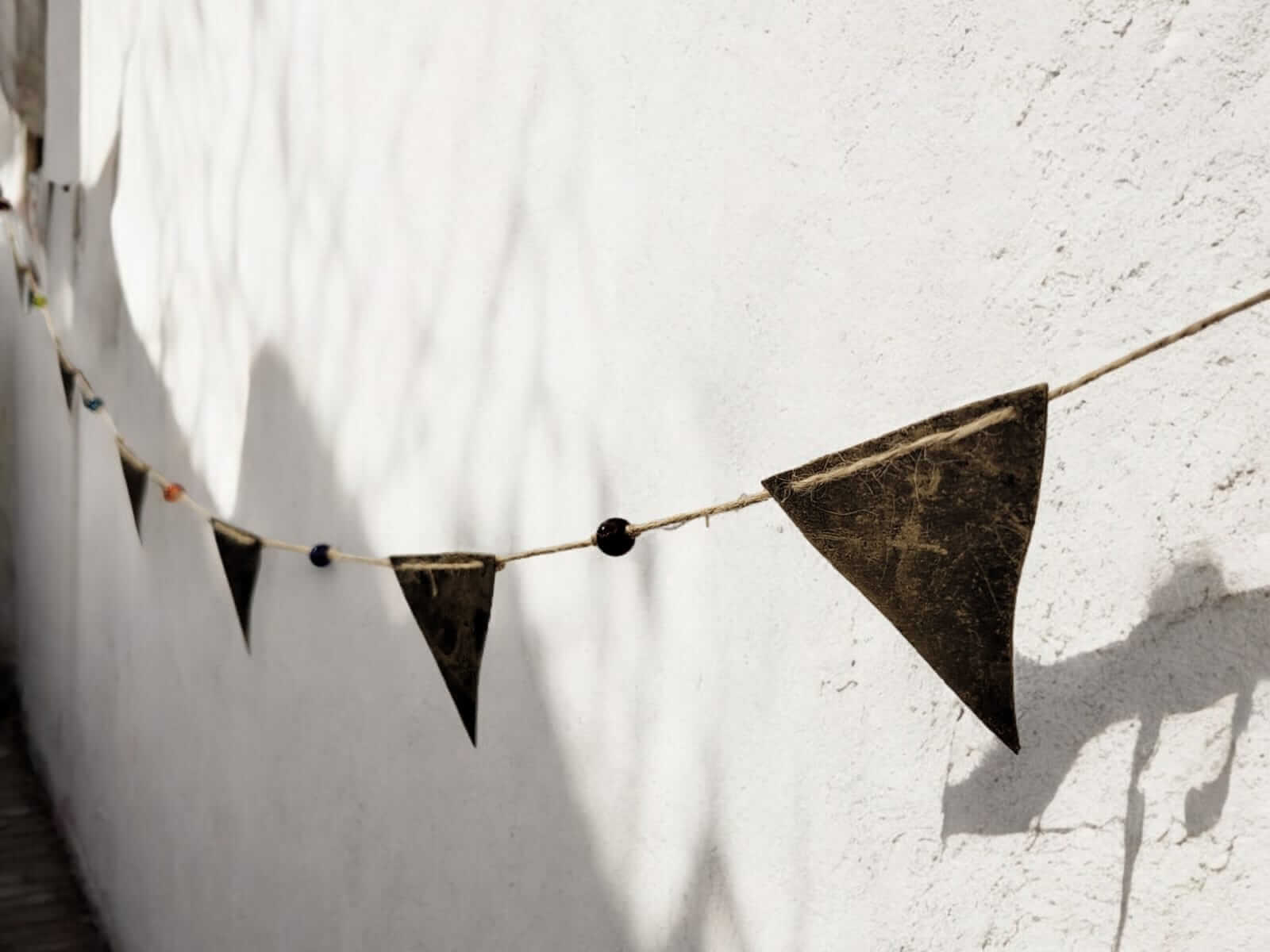 Vintage recycled iron triangle bunting garland hanging on a wall, perfect for bohemian theme party or garden decor.