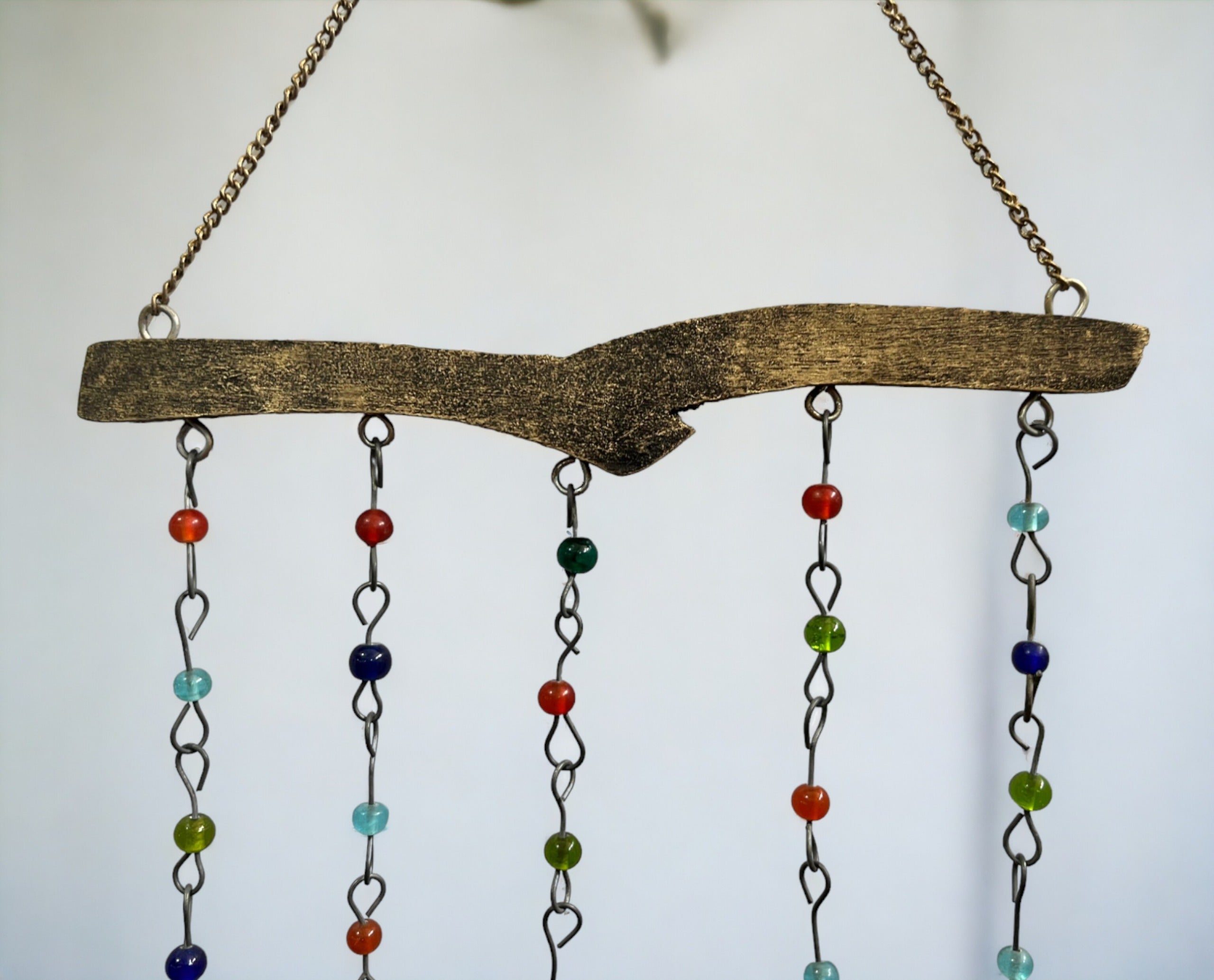 Handmade beaded wind chime with colorful glass beads hanging from a rustic wooden frame.