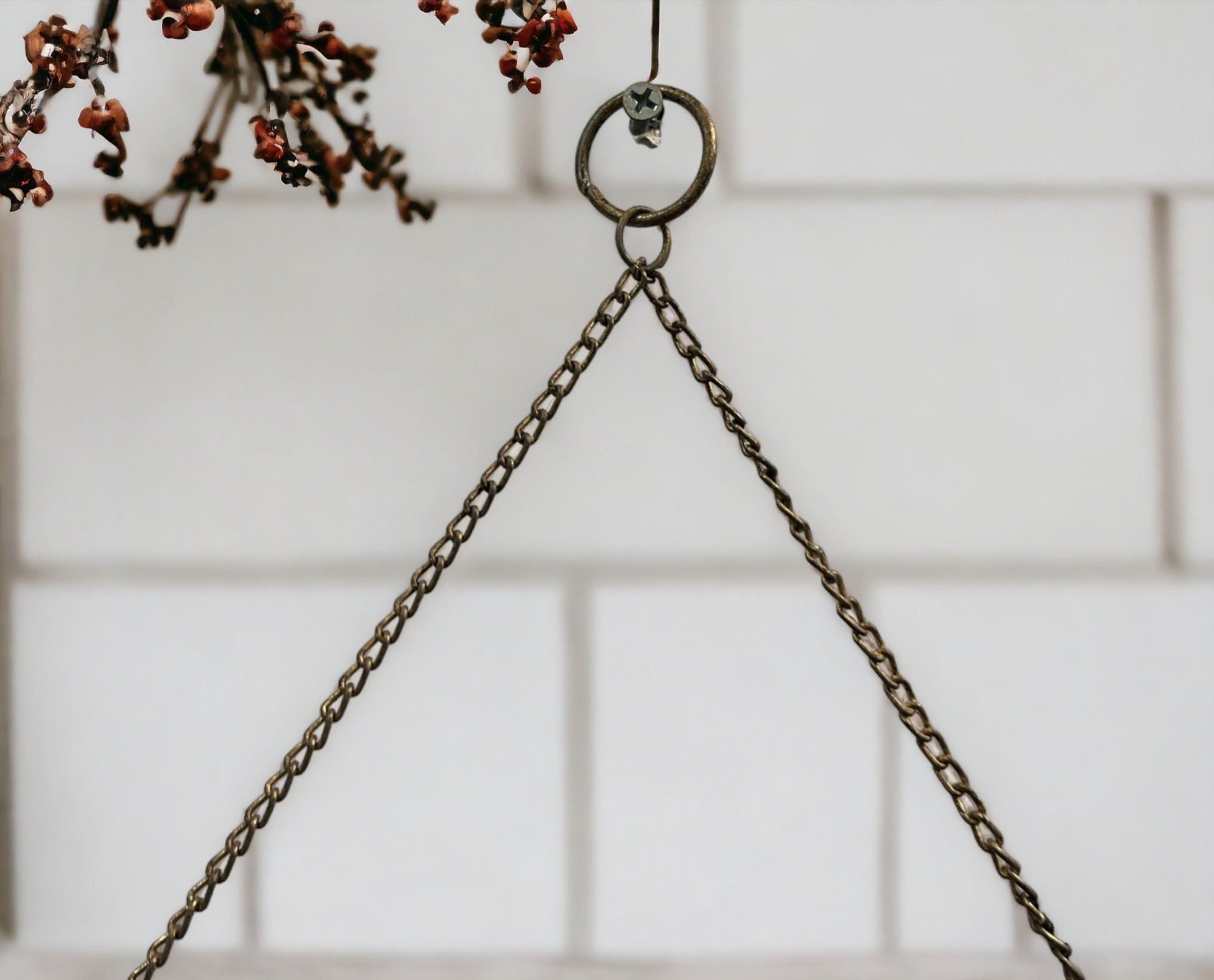 Hanging iron chain mobile holder with decorative flower accents against tiled background.