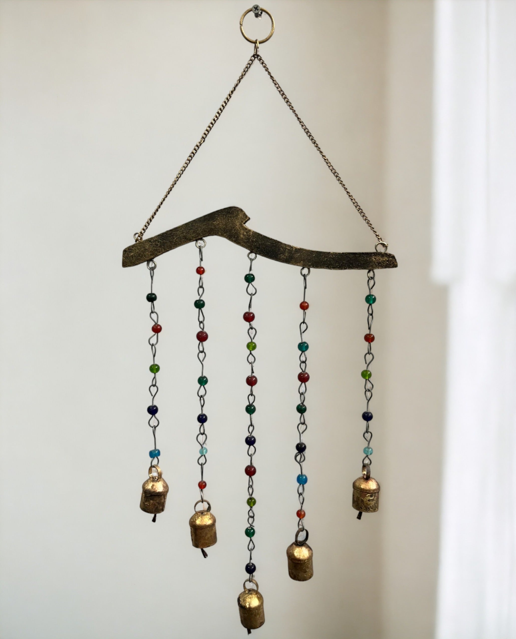 Handmade iron wind chime with colorful glass beads and decorative bells in bohemian design.