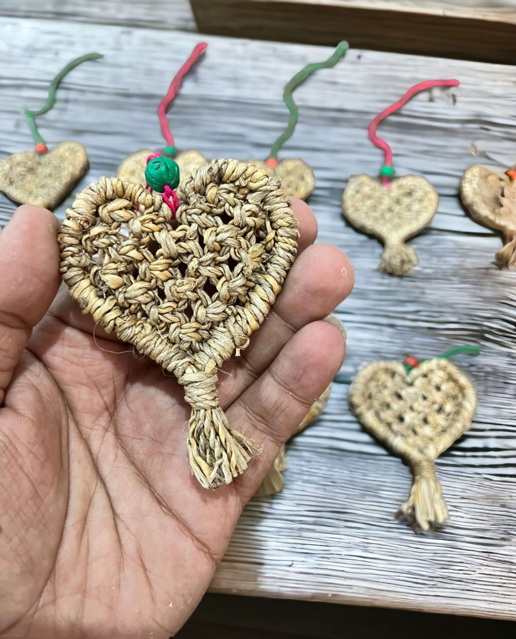 Handwoven heart ornament made from banana fiber, eco-friendly Christmas decoration held in hand, showcasing craftsmanship.