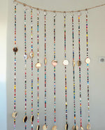 Colorful bohemian beaded curtain with glass beads and metal bells, perfect for doorways and wall hanging décor.