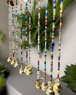 Colorful bohemian beaded curtain with glass beads and metal bells, perfect for hippie home decor and doorway accents.