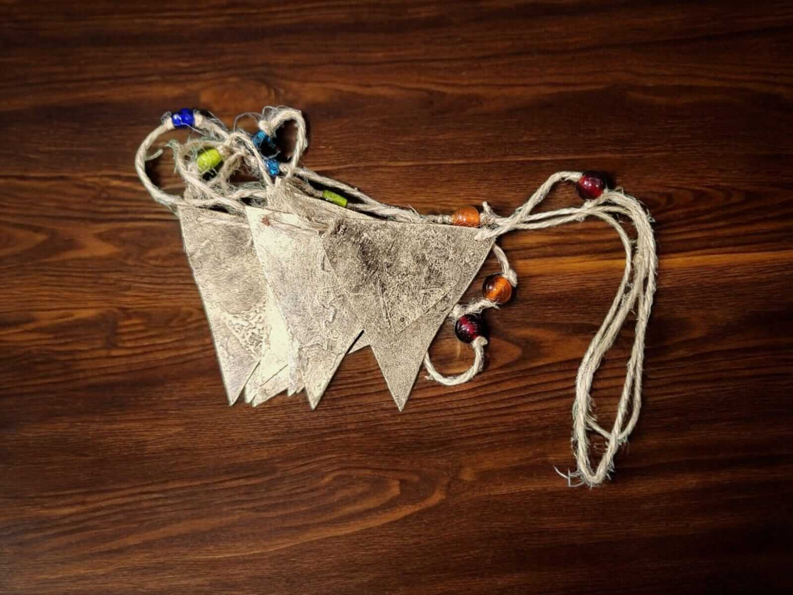 Recycled iron metal triangle bunting garland with multicolor glass beads on jute string, showcasing vintage style décor.