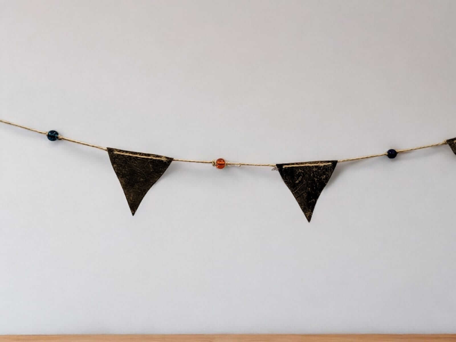 Antique gold recycled iron triangle bunting garland with multicolored glass beads for bohemian party décor.