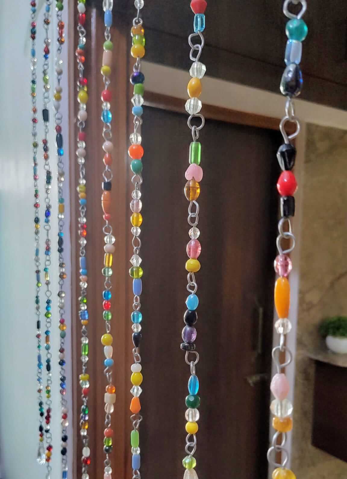 Colorful bohemian glass bead strands hanging as a beaded curtain for doorways, showcasing unique handmade designs.