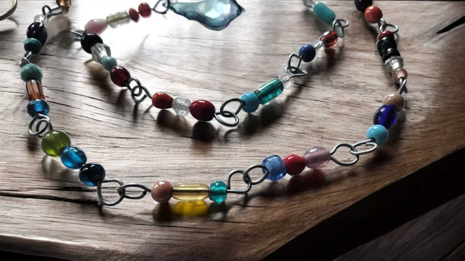 Colorful glass bead strands on a wooden surface, featuring handmade, durable beaded curtain chains for hippie decor.
