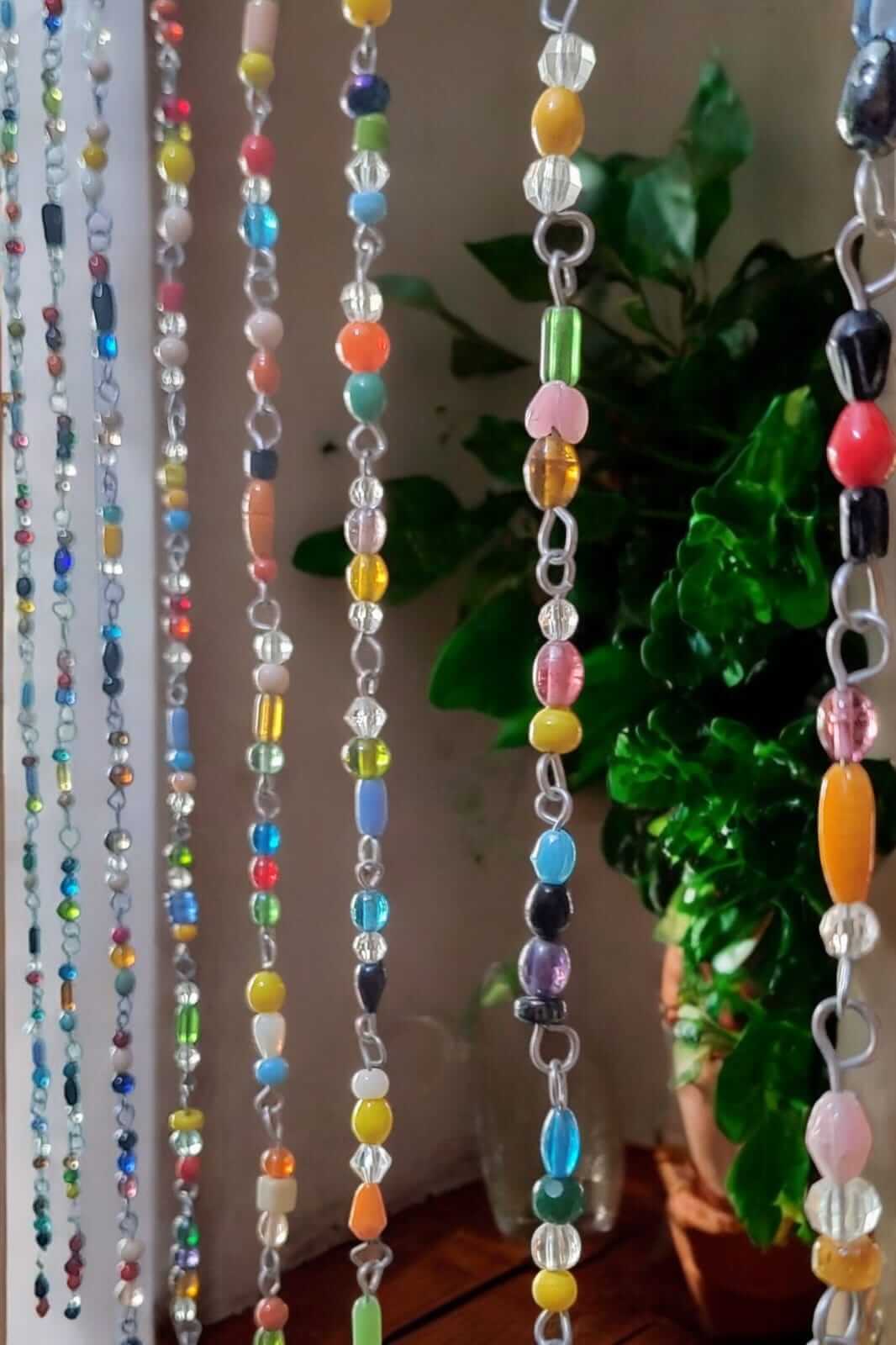 Colorful glass bead strands hanging as a beaded curtain, ideal for doorways and hippie decor.