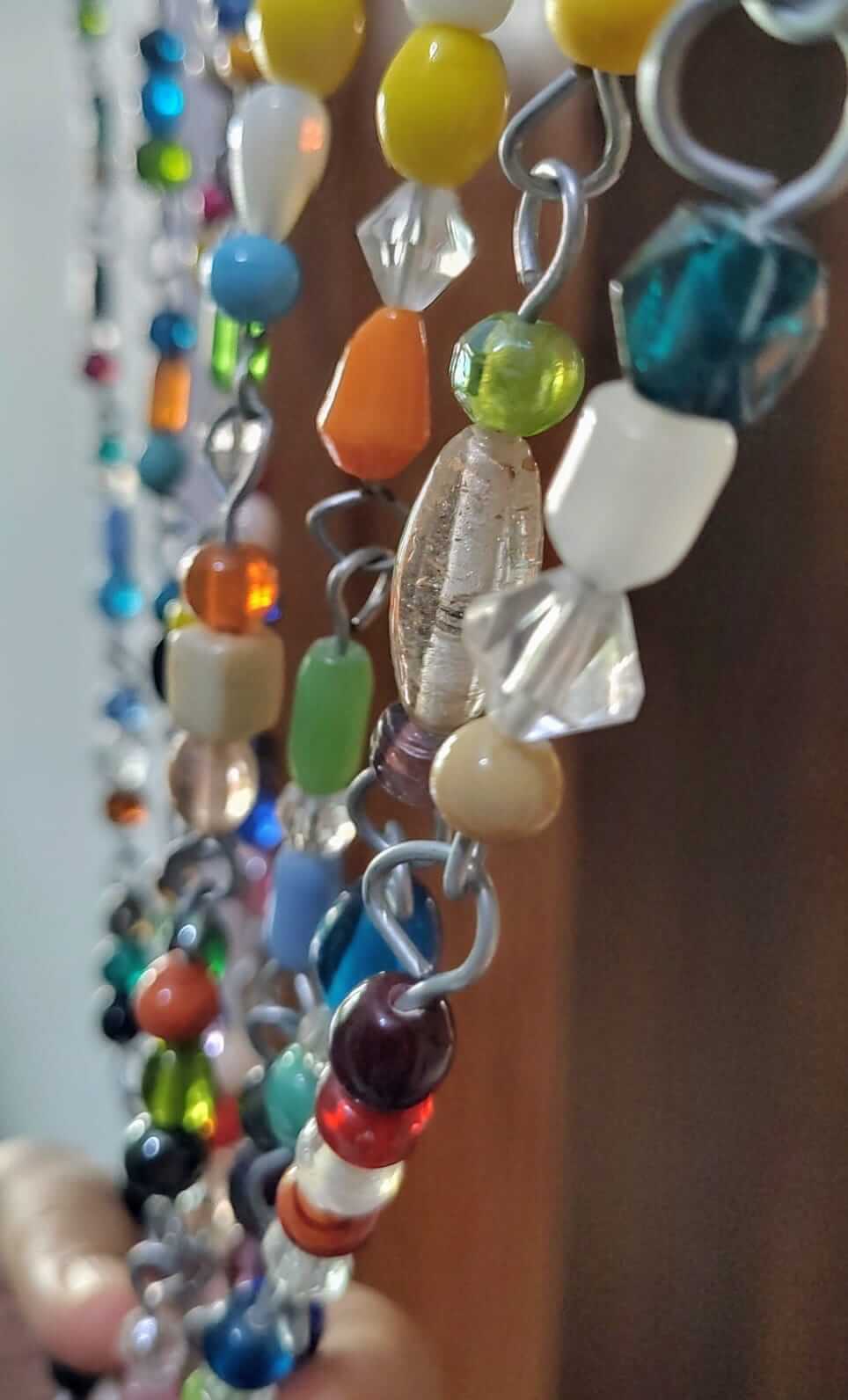 Close-up of colorful glass bead strands for hippie curtains and doorways, showcasing unique handmade designs.