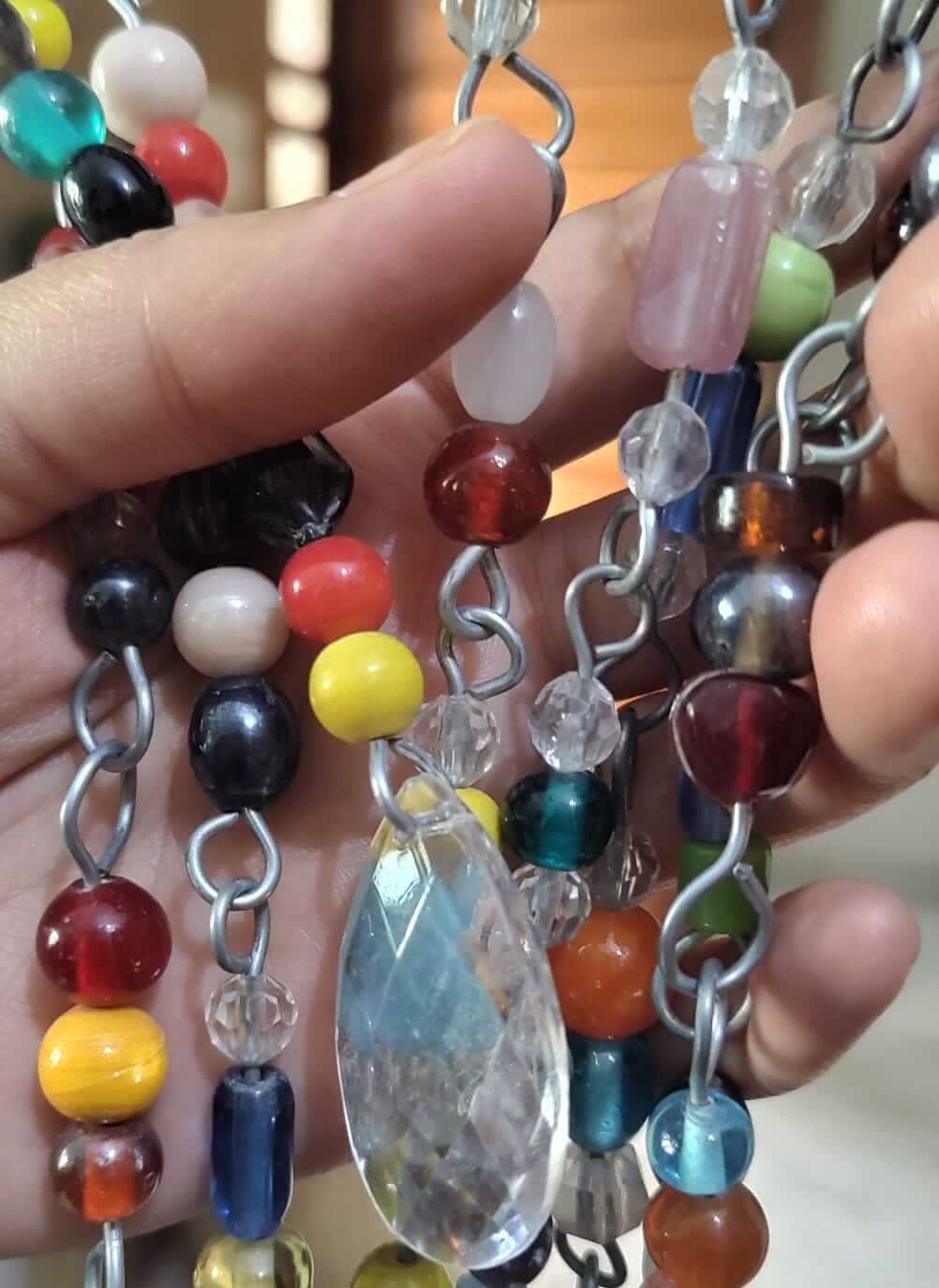 Colorful glass bead strands held in hand, showcasing unique hippie beaded curtain designs for doorways.