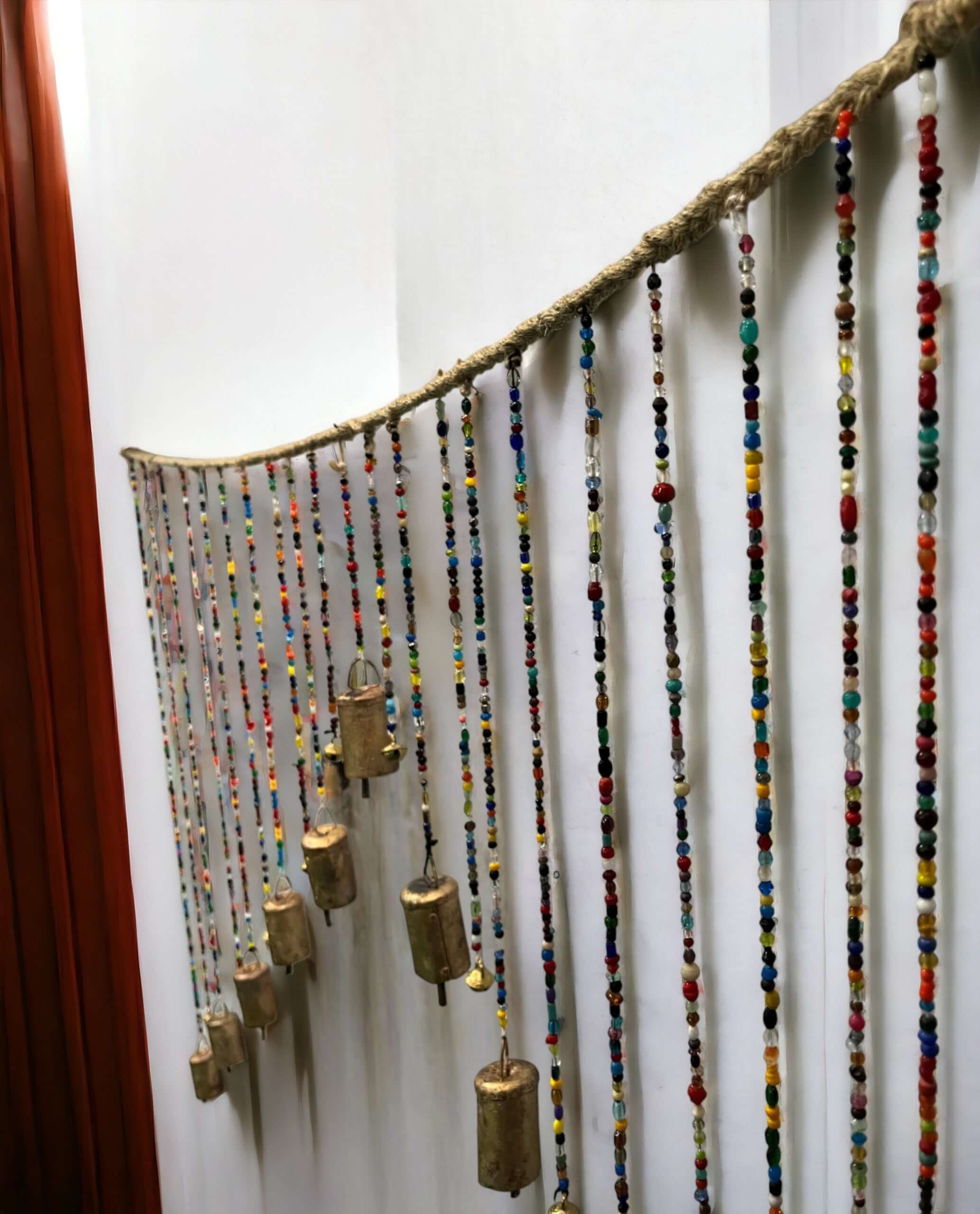 Multicolour beaded wall door hanging valance with brass bells, perfect for bohemian home decor.