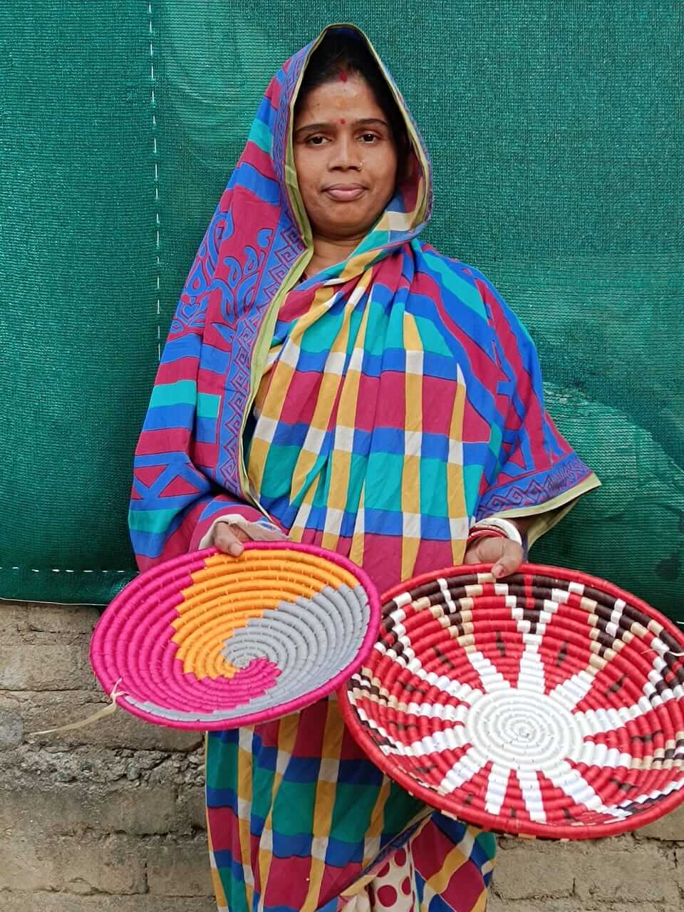 Woman showcasing handmade colorful Sabai grass woven baskets, highlighting eco-friendly craftsmanship.