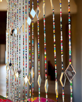 Colorful bohemian beaded curtain with glass beads and mirrors, ideal for doorways and wall decor.