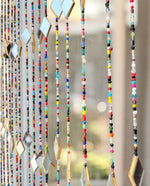 Colorful beaded curtain with glass beads and metal accents, perfect for hippie home decor and doorway decoration.