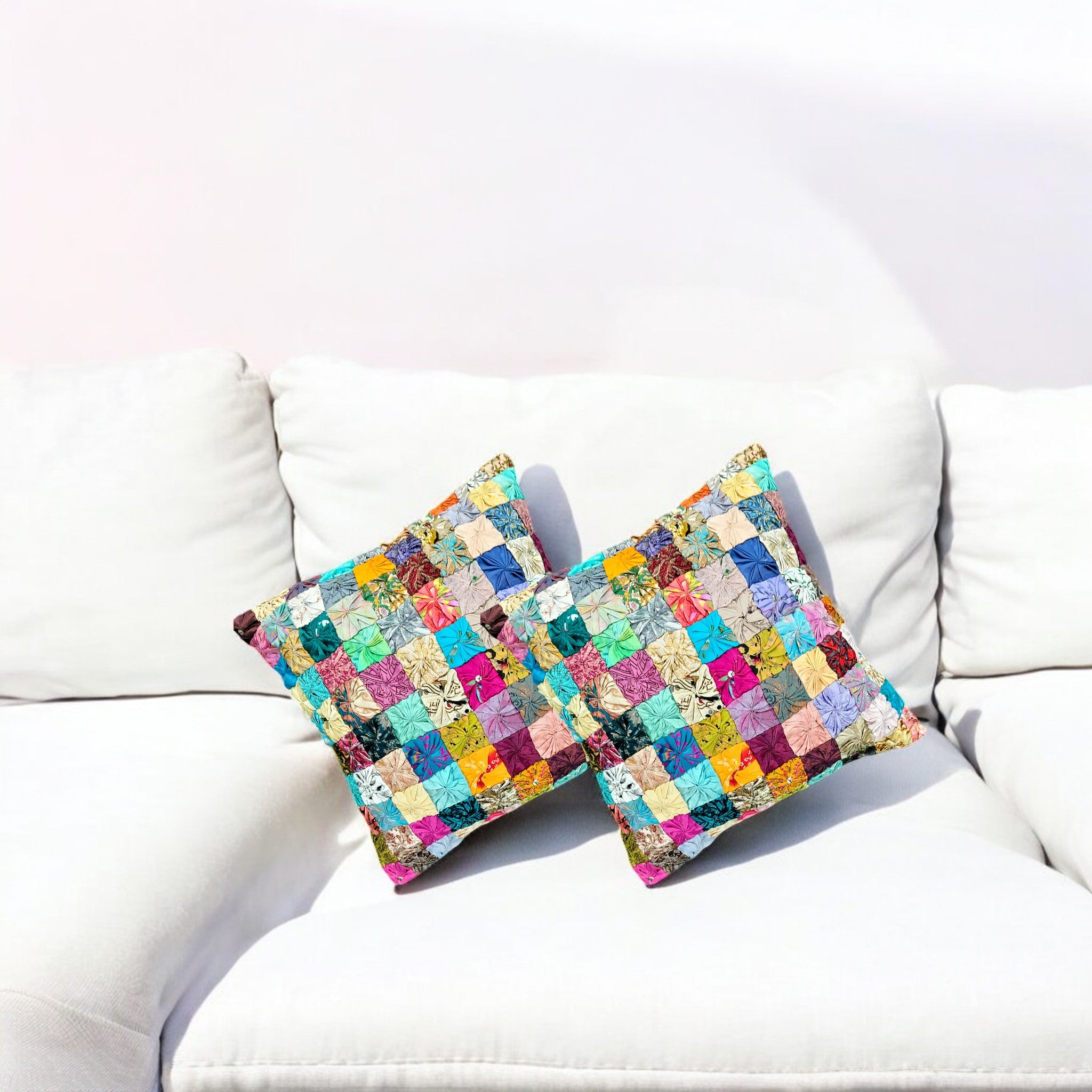 Colorful handmade patchwork cushion covers on a white couch, adding a vibrant touch to home decor.