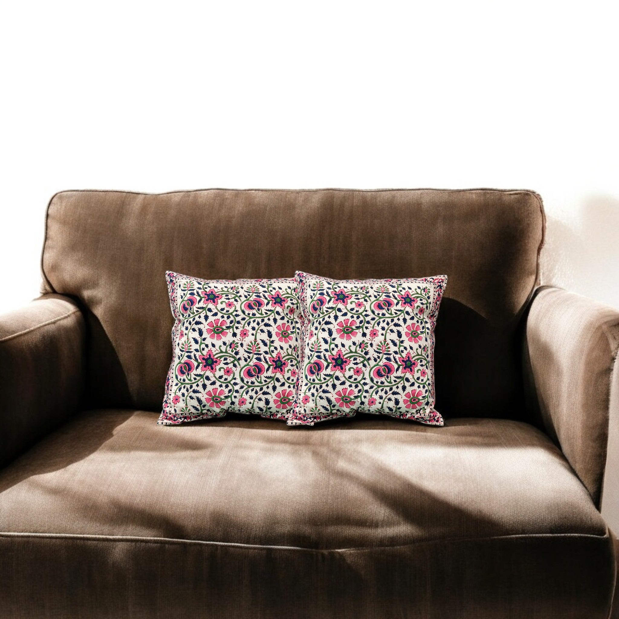 Set of 2 floral embroidered cushion covers on a brown sofa, enhancing cozy home decor.