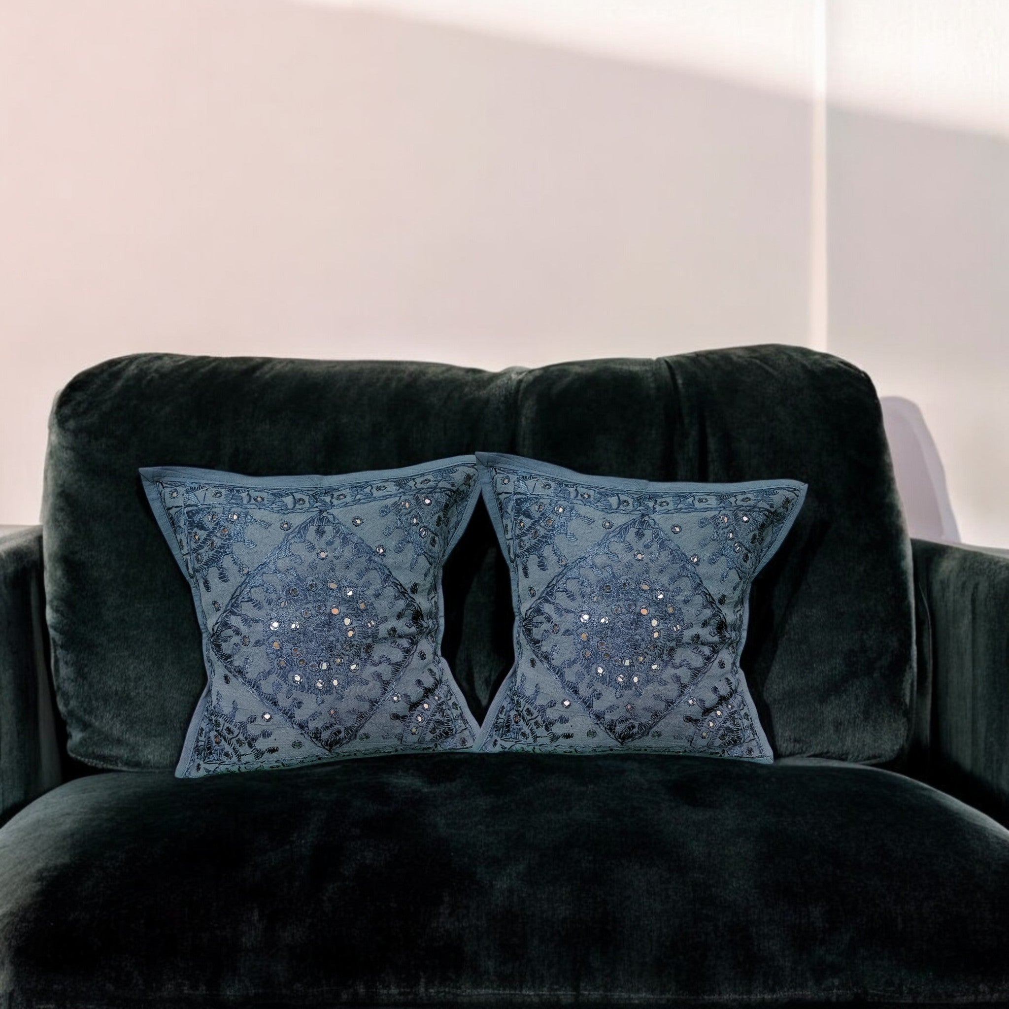 Handmade dark blue mirror work cushion covers on a plush black sofa, adding elegance to home decor.