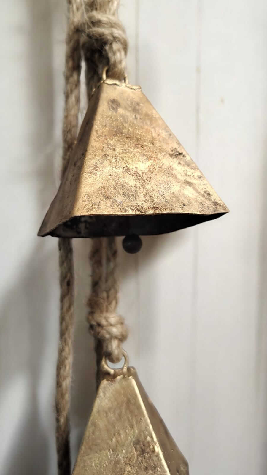 Rustic vintage metal bell hanging from jute rope, perfect for tranquil wind chimes and garden decor.