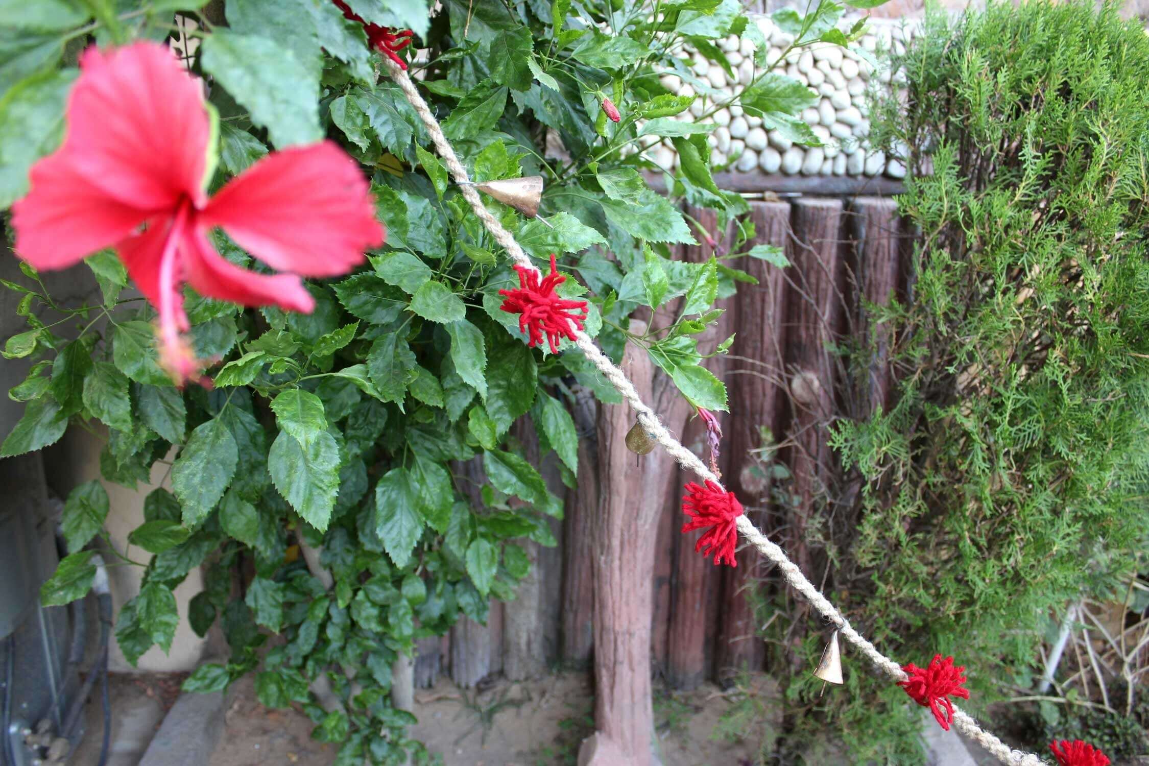 Vintage cow bells and red tassels on jute string garland, perfect for outdoor garden decoration.
