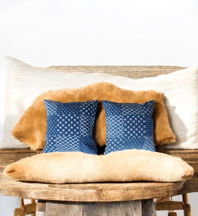 Set of 2 indigo blue geometric decorative throw pillows on a rustic wooden bench, accenting plush cushions.