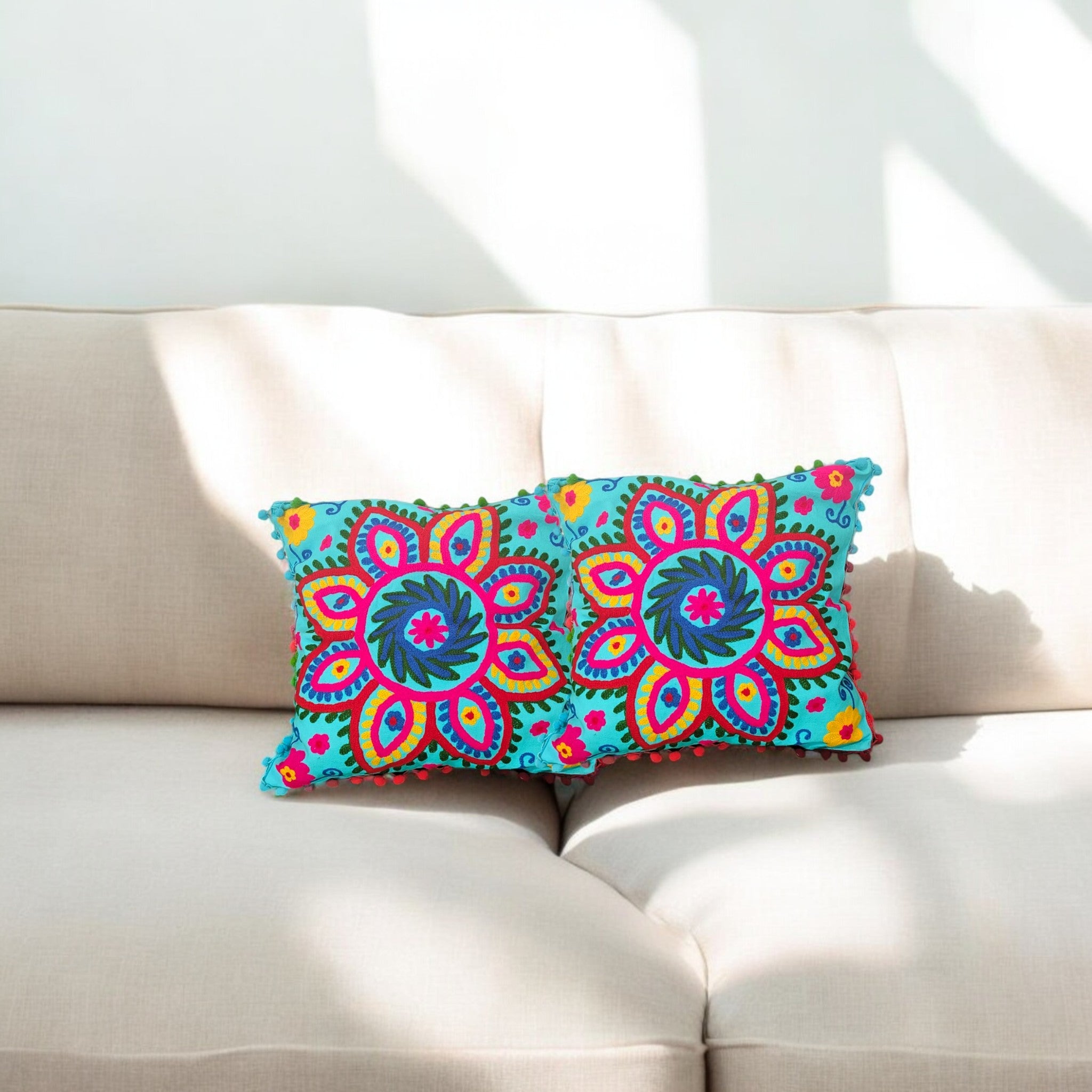 Multicolor floral embroidered cushion covers with pom-pom edges on a sofa, decorative throw pillows set of 2.
