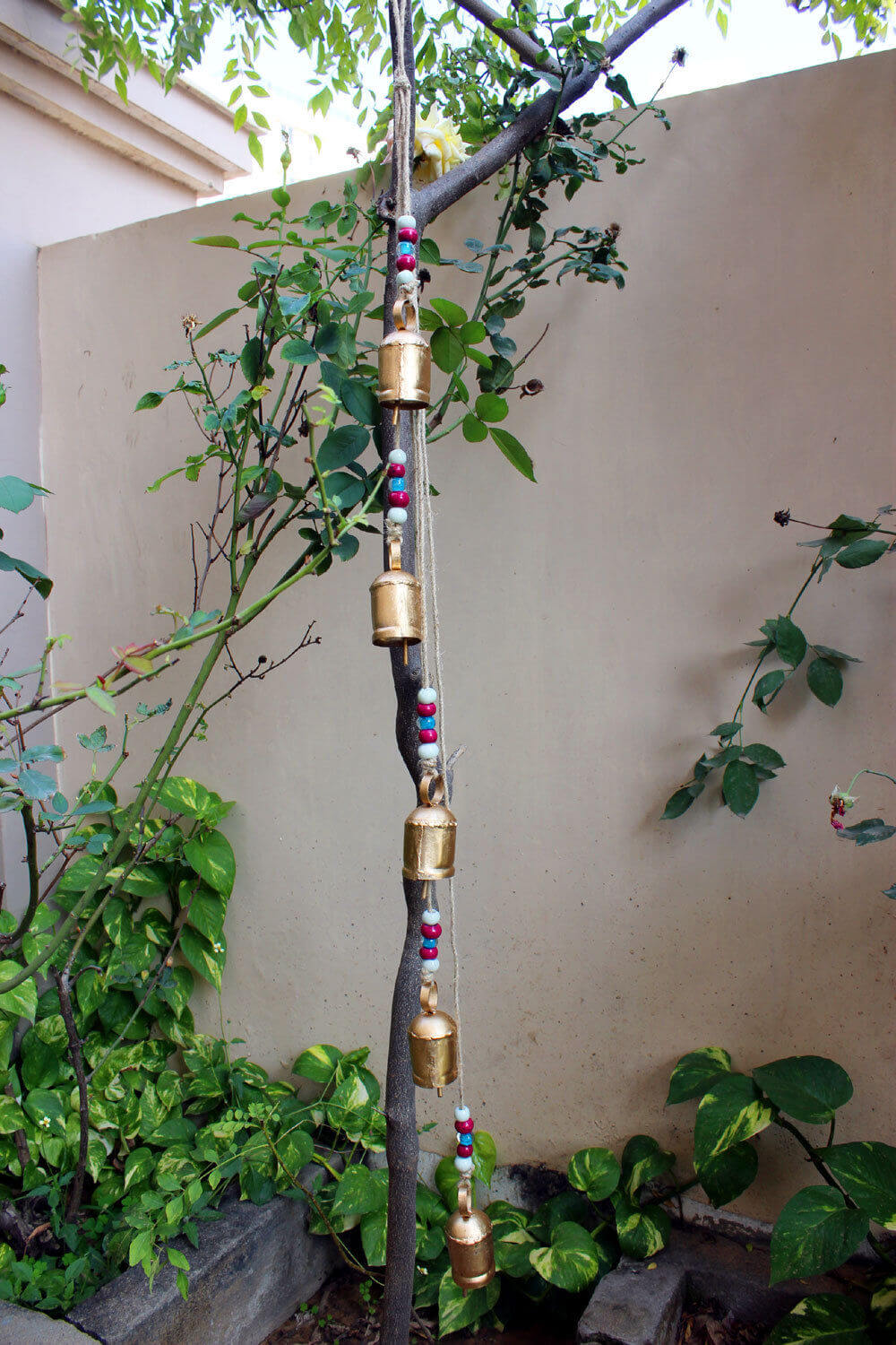 Hanging antique look wind chime with metal bells and colorful beads, perfect for outdoor garden decor.