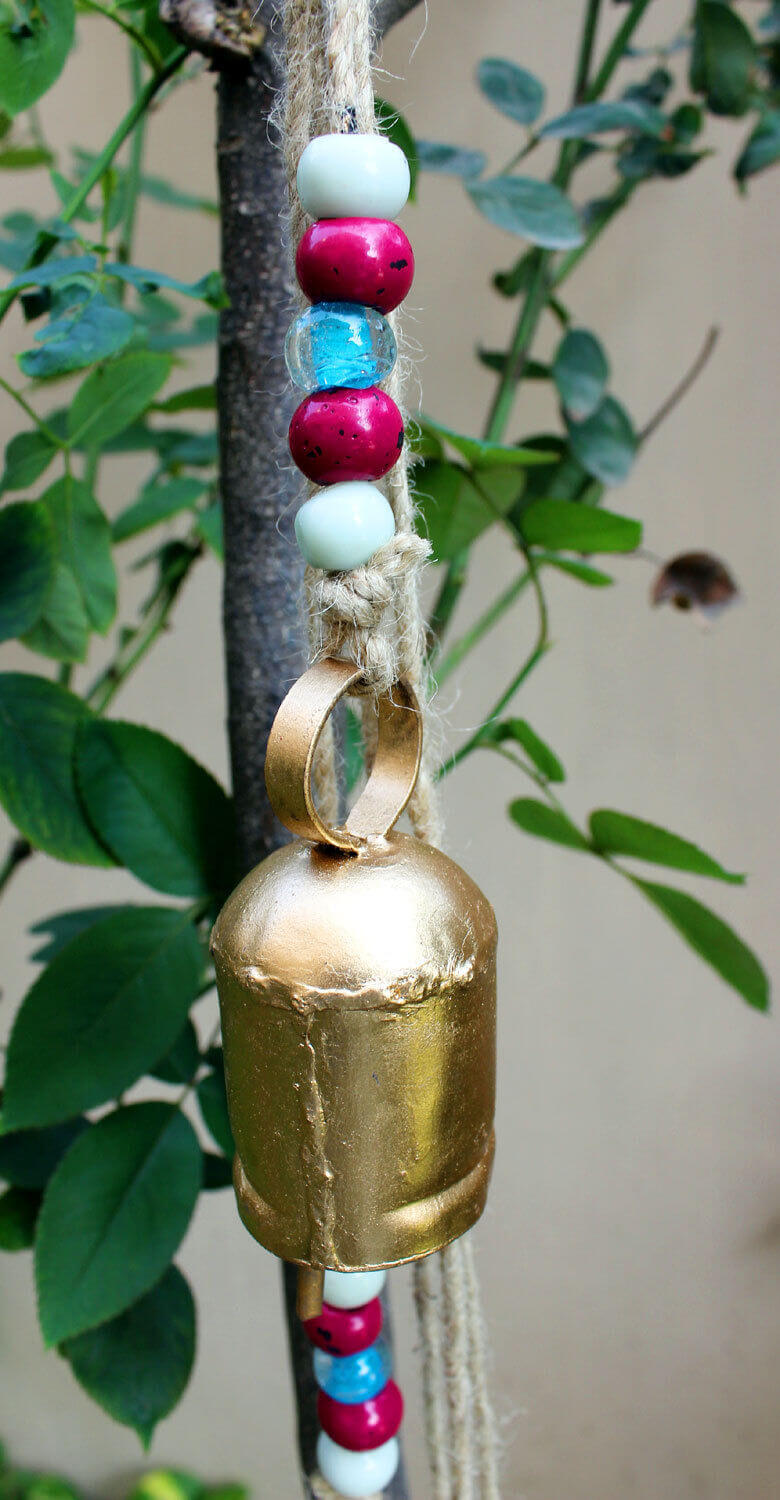 Antique wind chime bell with colorful beads, perfect for garden decor and adding a rustic charm to outdoor spaces.