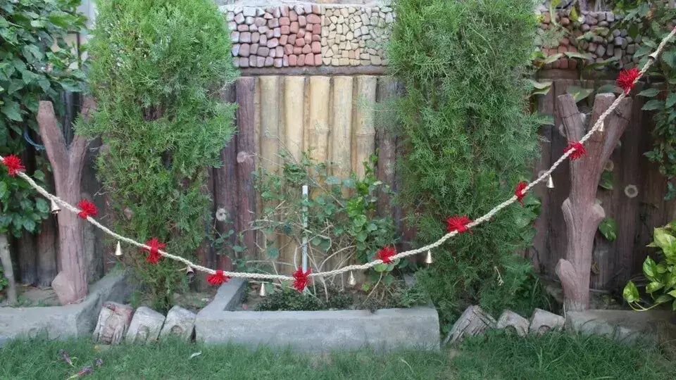 Vintage cow bells garland on jute string with red tassels, perfect for outdoor garden decoration.