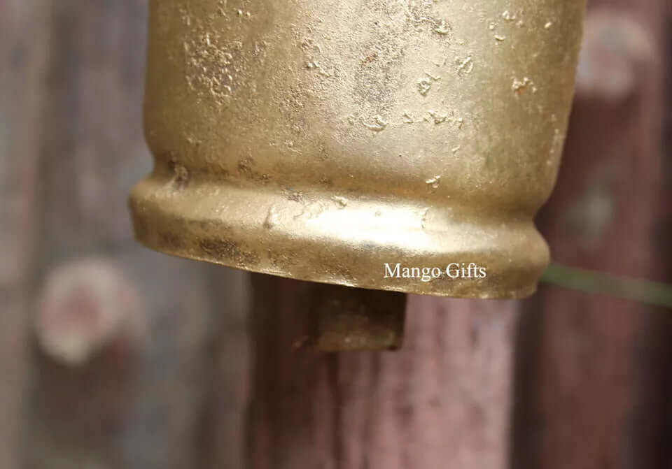 Close-up of a handcrafted recycled iron bell showcasing its rustic gold finish and elegant design.