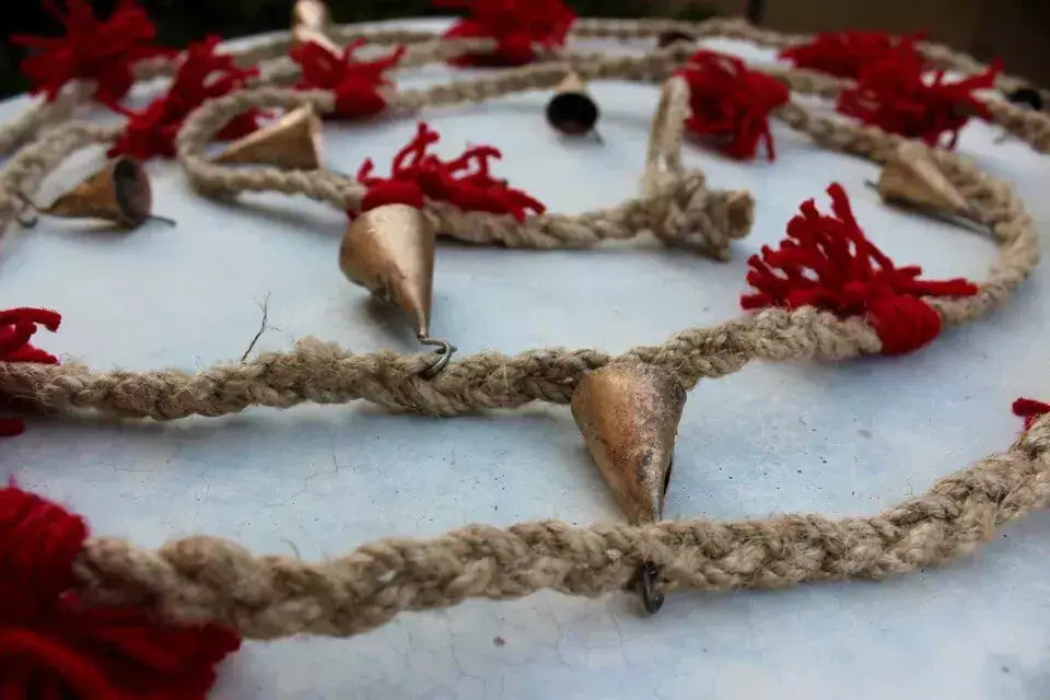 Vintage cow bells on jute rope garland with red tassels, perfect for garden and outdoor decoration.
